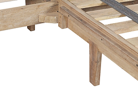 Close-up of the Iya Reclaimed Wood Bed - Natural by nkuku, showing its rustic corner with slats and angled legs, and highlighting the natural wood grain and craftsmanship against a white background.