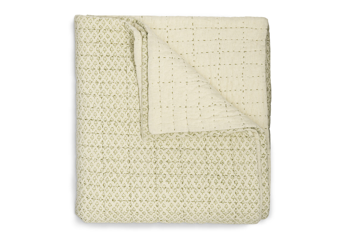 The Peplu Cotton & Linen Screen Print Bed Quilt by nkuku features a sage green floral pattern on a cream background, with a stitched square grid reverse—blending elegance and Indian textile heritage. Neatly folded and arranged on white.
