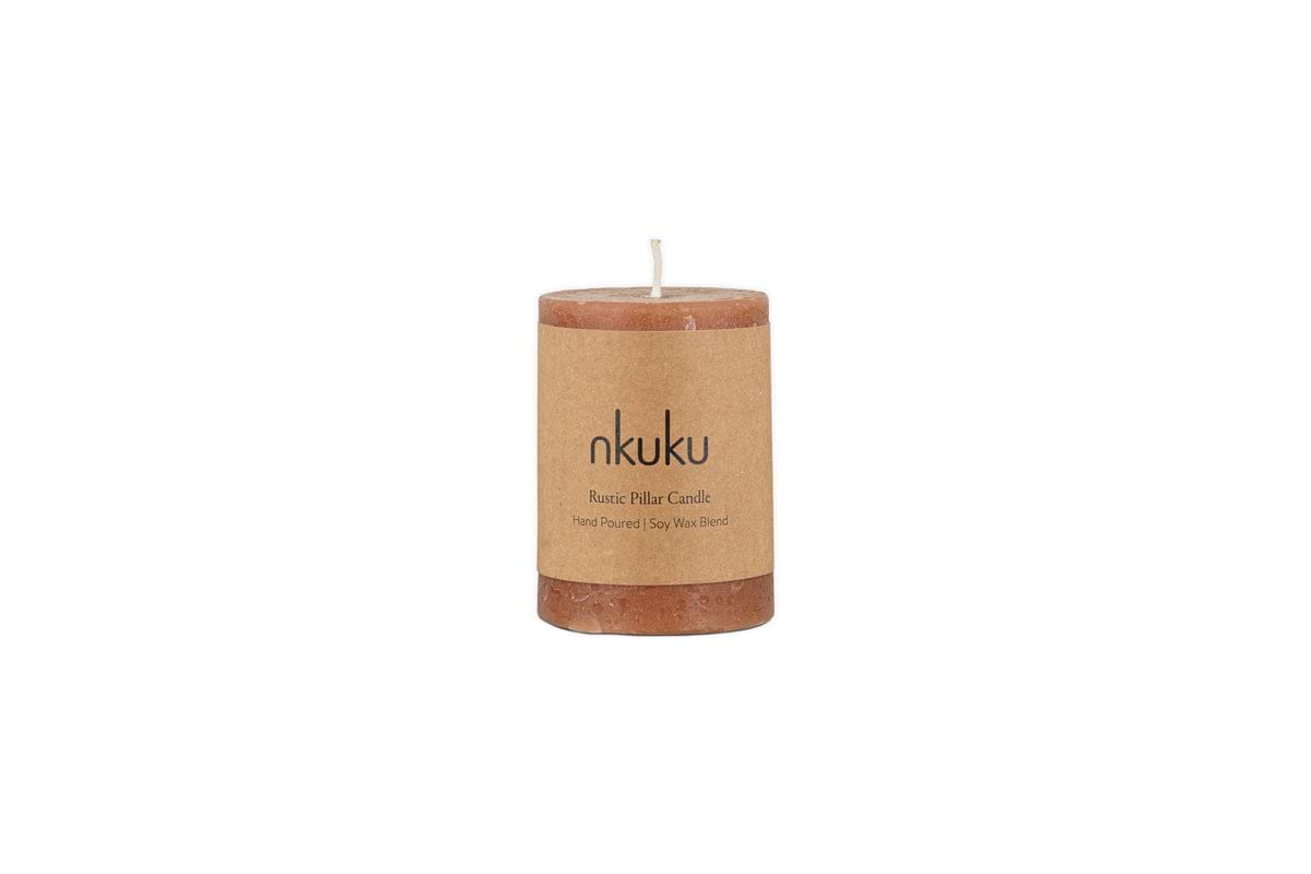 A Rustic Soy Blend Mini Pillar Candle in rust by nkuku with a textured finish and label, shown against a plain white background.