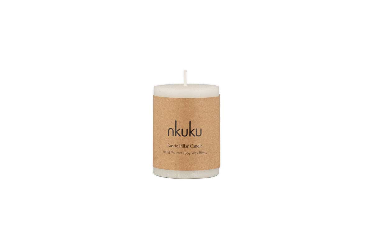 A white Rustic Soy Blend Mini Pillar Candle by nkuku, featuring a textured finish and a brown paper label, shown against a plain white background.
