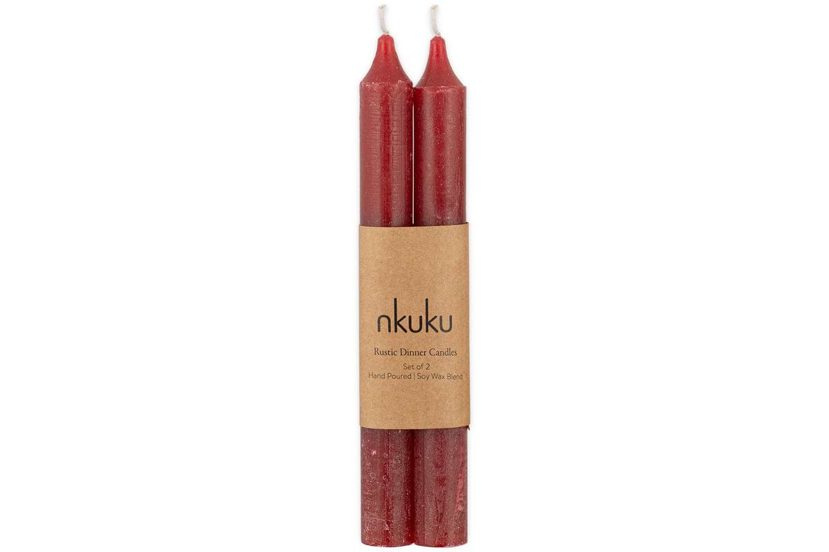 Two Rustic Soy Blend Dinner Candles in Dark Cherry by nkuku, hand-poured with a slightly textured finish, come as a set of 2 bundled together with a brown paper label that reads “nkuku Rustic Dinner Candles.”.