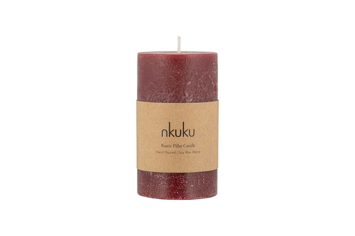 A small nkuku Rustic Soy Blend Pillar Candle in Dark Cherry with a textured finish and a brown paper label stands upright on a white background.