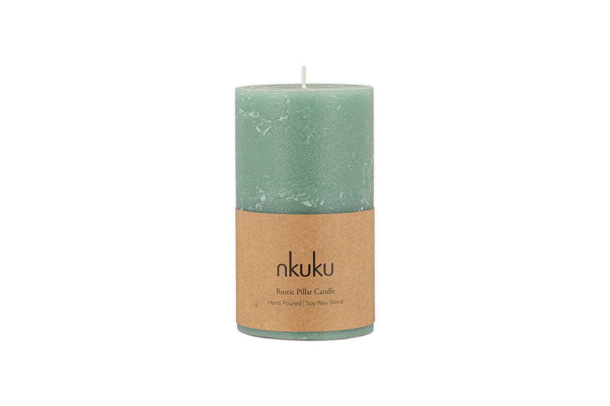 A small sage green Rustic Soy Blend Pillar Candle by nkuku, featuring a textured finish and a brown label, is shown against a white background.