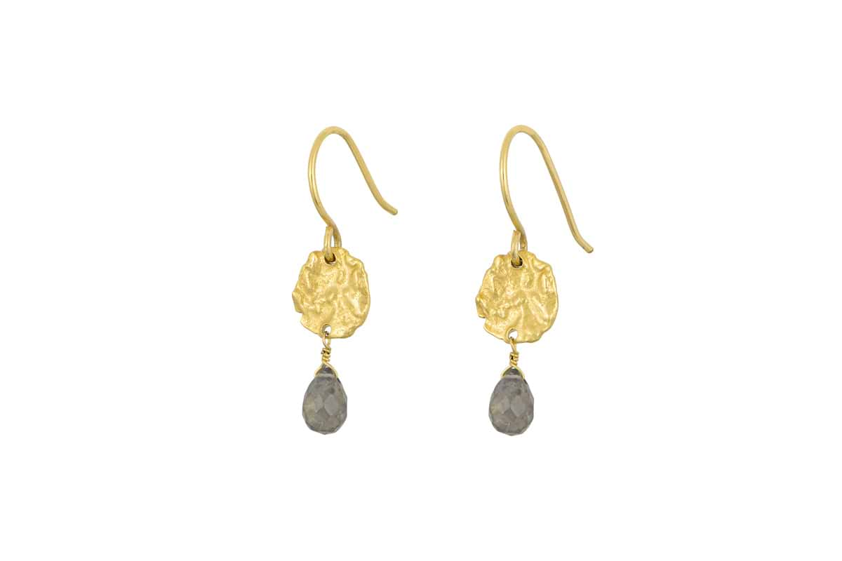 The Veera Labradorite Earrings - Gold by nkuku feature textured gold-toned discs with teardrop-shaped gray labradorite gemstones hanging below, set against a white background.