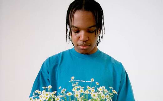 Man in blue shirt looking down at bouquet of flowers Phoenix - Futures - Ripple+