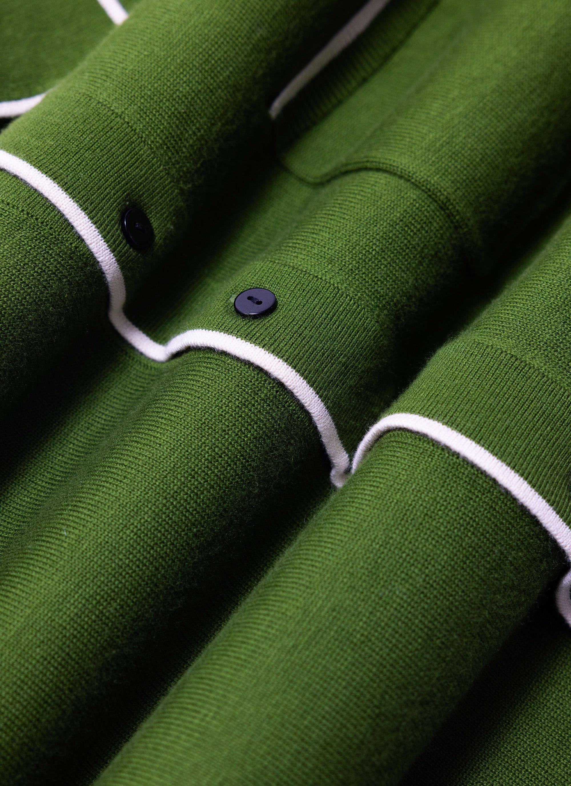 A close-up of the Percival Contrast Trim Shirt in forest green, showing the wool-blend knit texture and ecru trim detail.