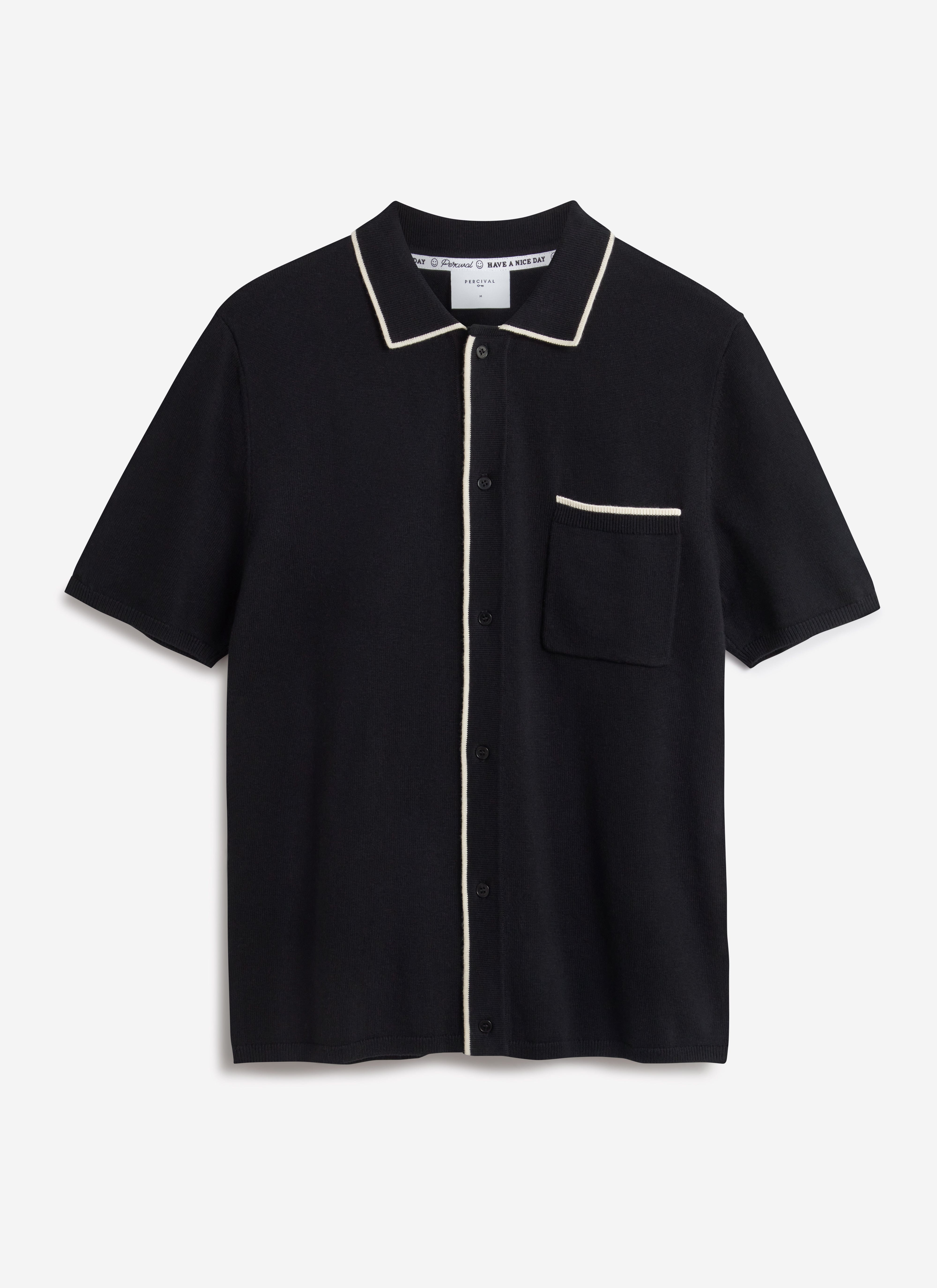 A flat lay image of the Percival Contrast Trim Knitted Shirt in black, highlighting the ecru trim on the collar and pocket.