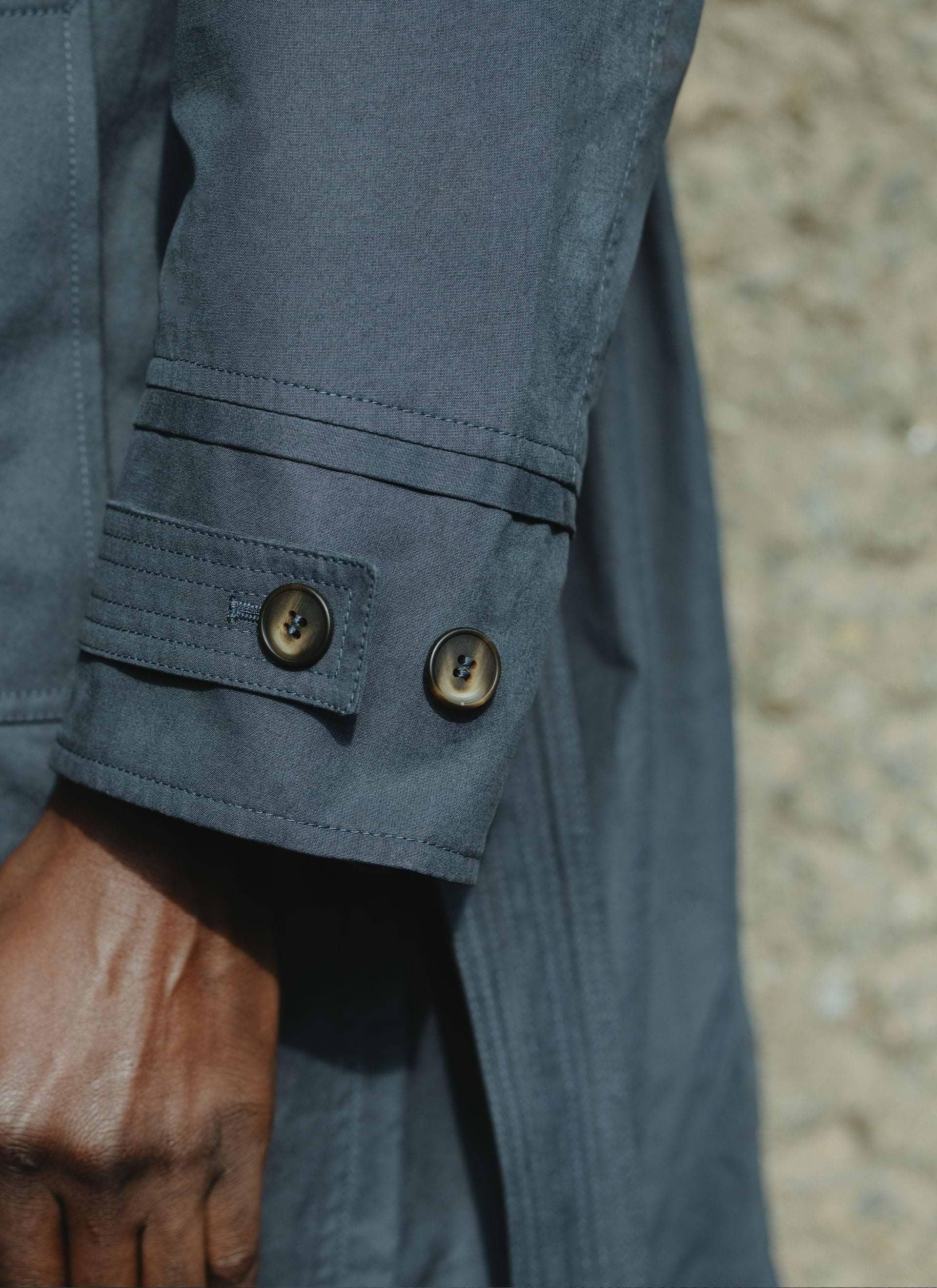 Close-up of the navy peached cotton sleeve cuff and buttons on the Front Office x Percival Mac Coat.