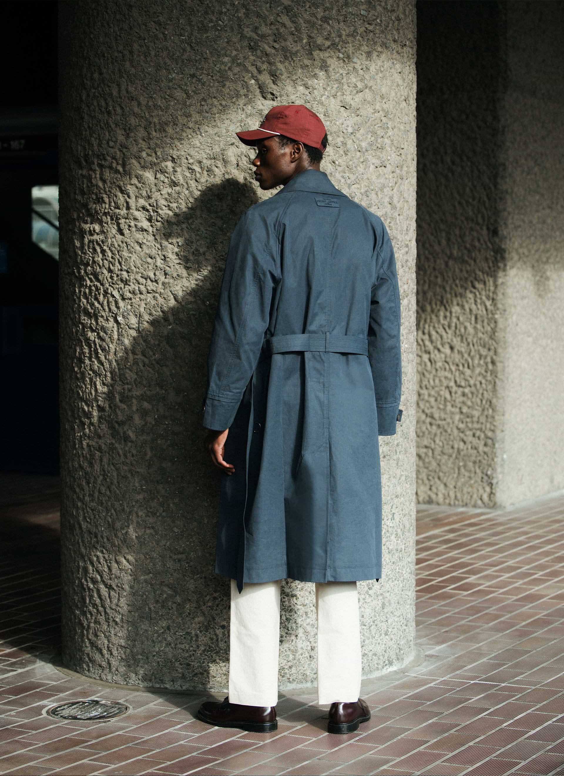 Rear view of the navy cotton Front Office x Percival Mac Coat, showcasing the belted waist and raglan sleeve construction.
