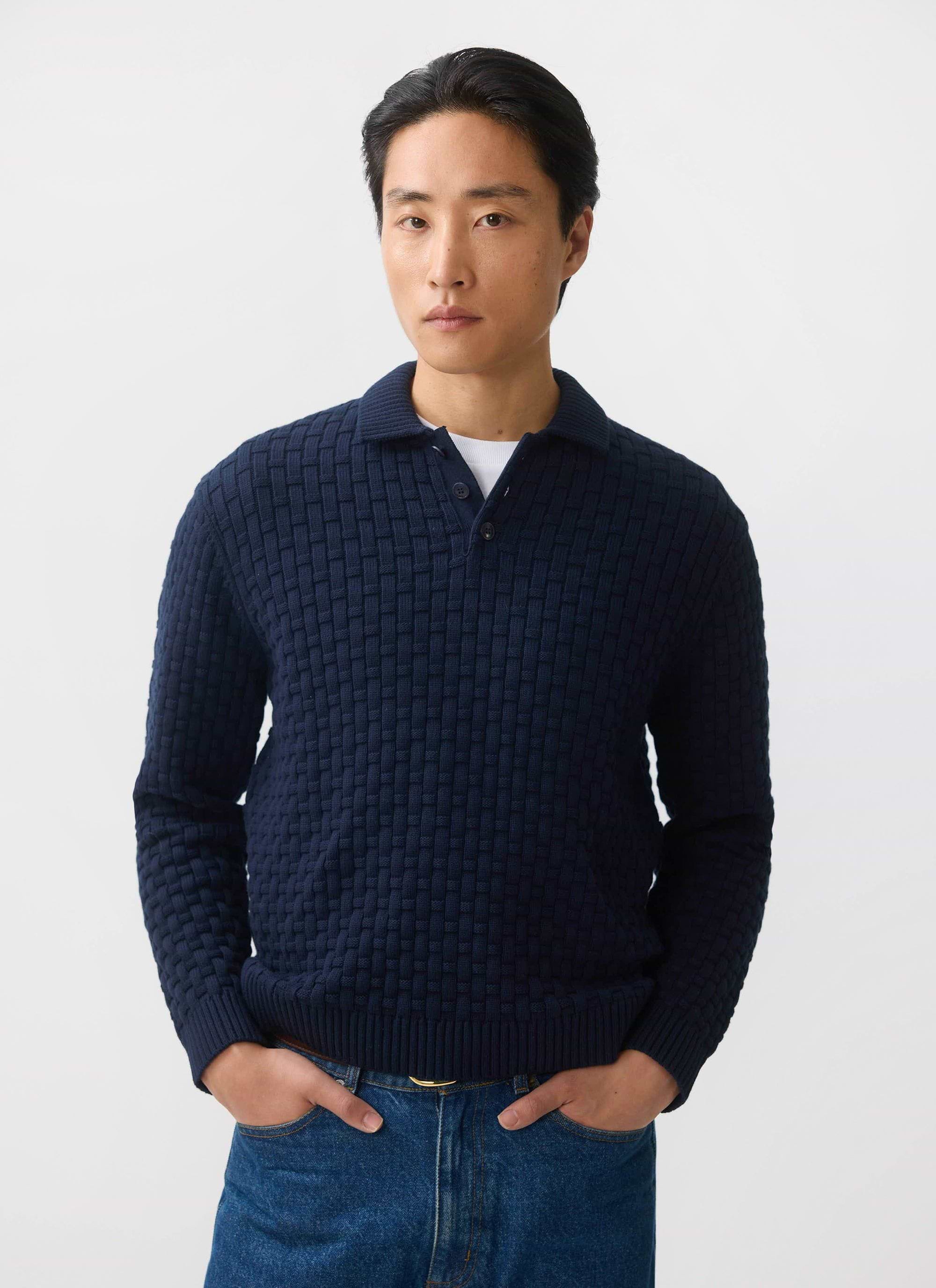 A model wears the Percival Archer Basketweave Long Sleeve Knitted Shirt in navy blue with jeans against a white background.