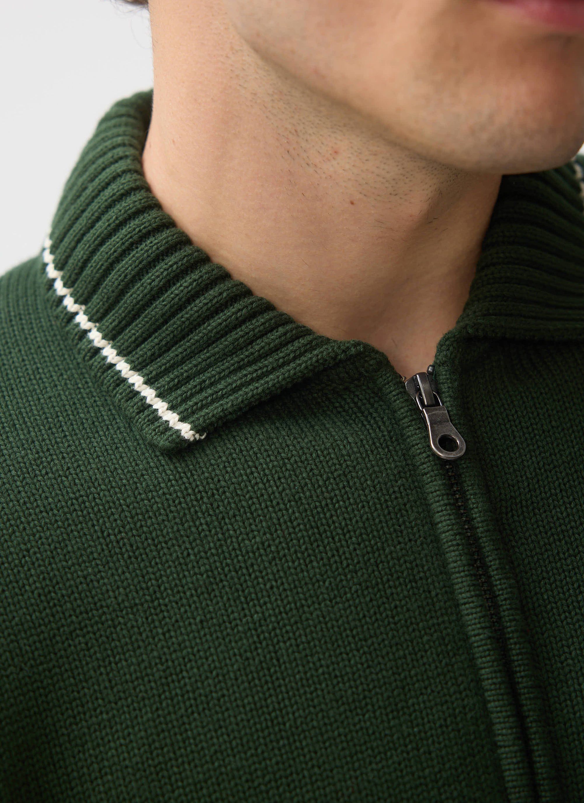 A close-up of the Percival Gardner Dense Knitted Zip Cardigan in forest green, showing the ribbed collar and zip detail.