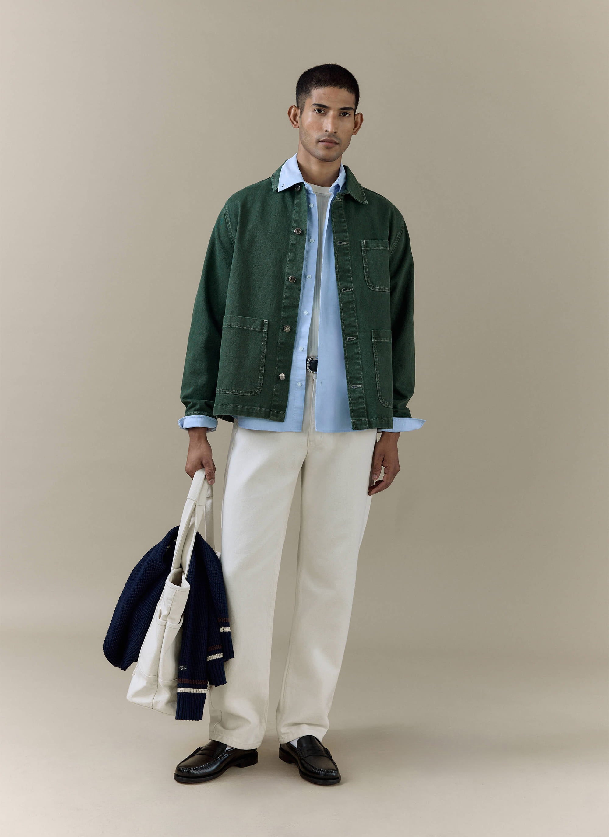 Model wearing the Percival Vintage Wash Oliver Chore Jacket in forest green cotton canvas with white trousers.