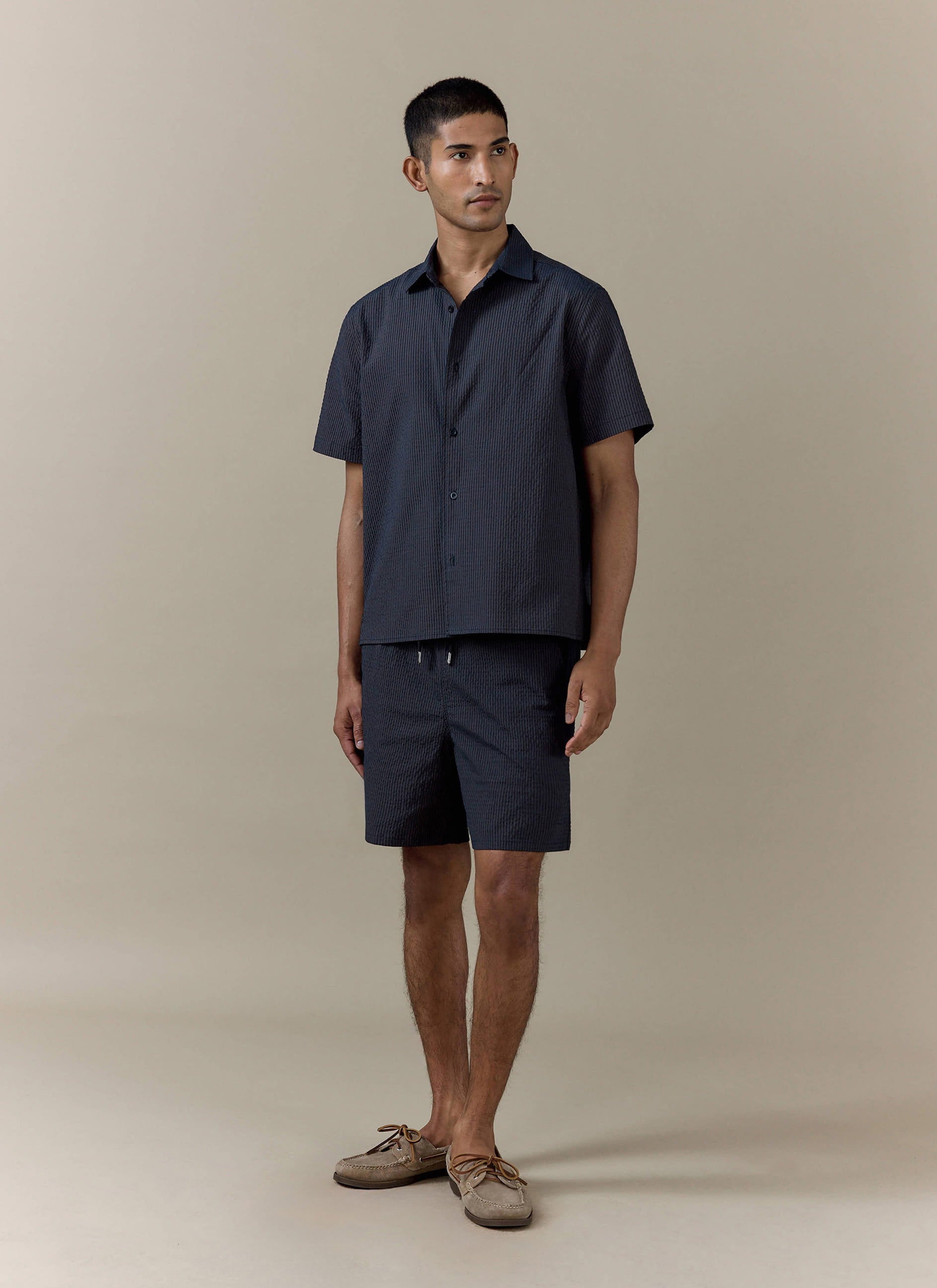 Navy stripe Rowan Seersucker Swim Shorts by Percival, styled as a matching set with a short-sleeved shirt.