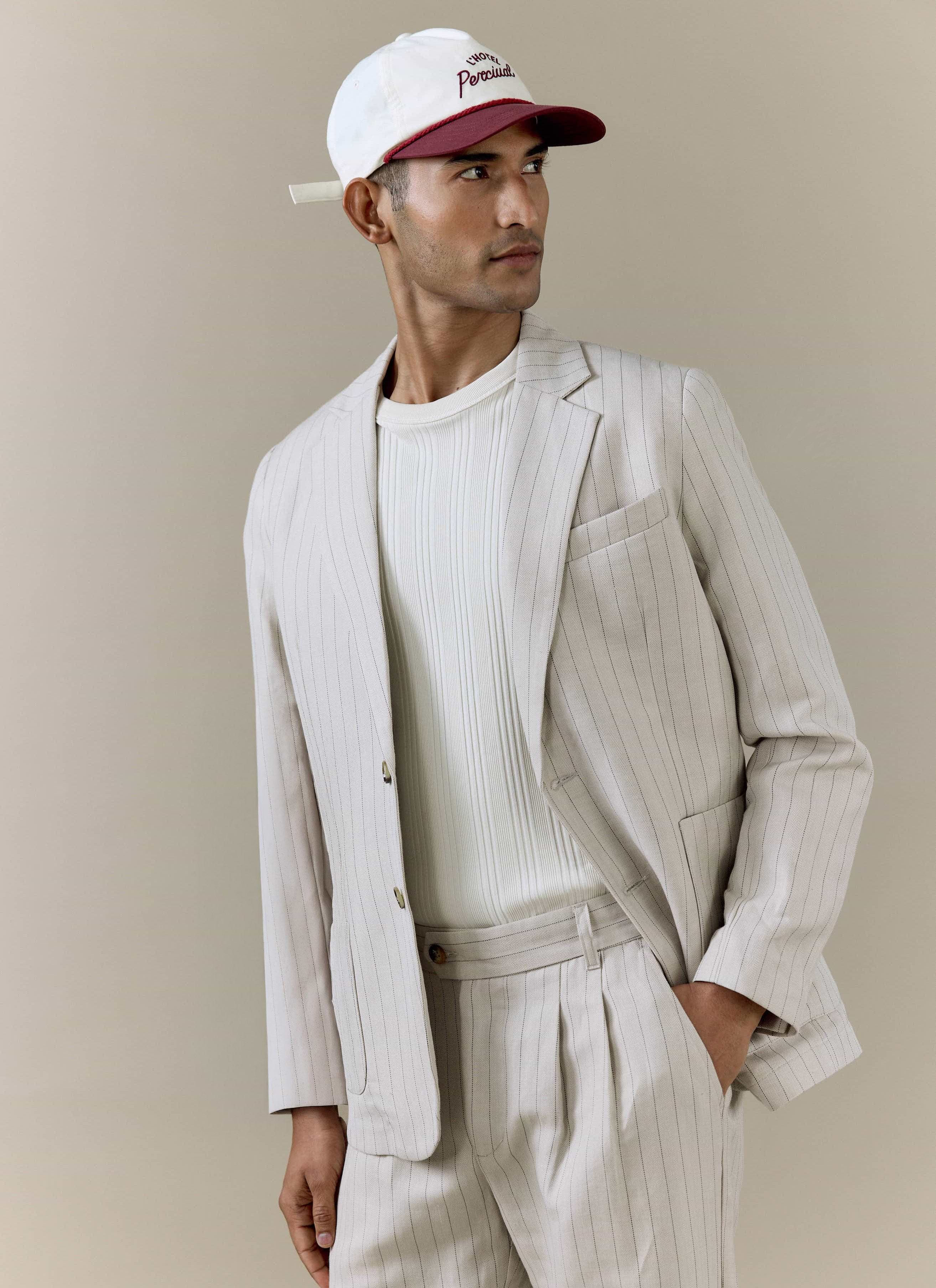 Percival cream striped tailored blazer and matching pleated trousers in a linen blend, styled with a branded cap.