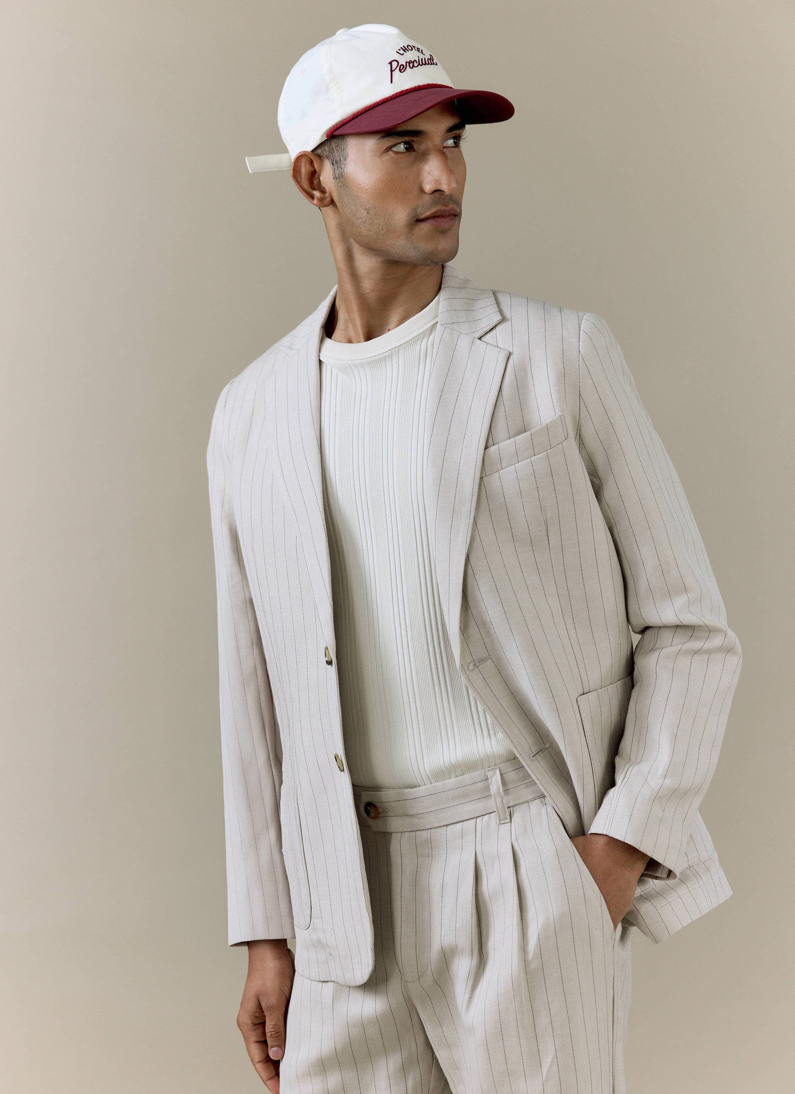 Percival cream striped tailored blazer and matching pleated trousers in a linen blend, styled with a branded cap.