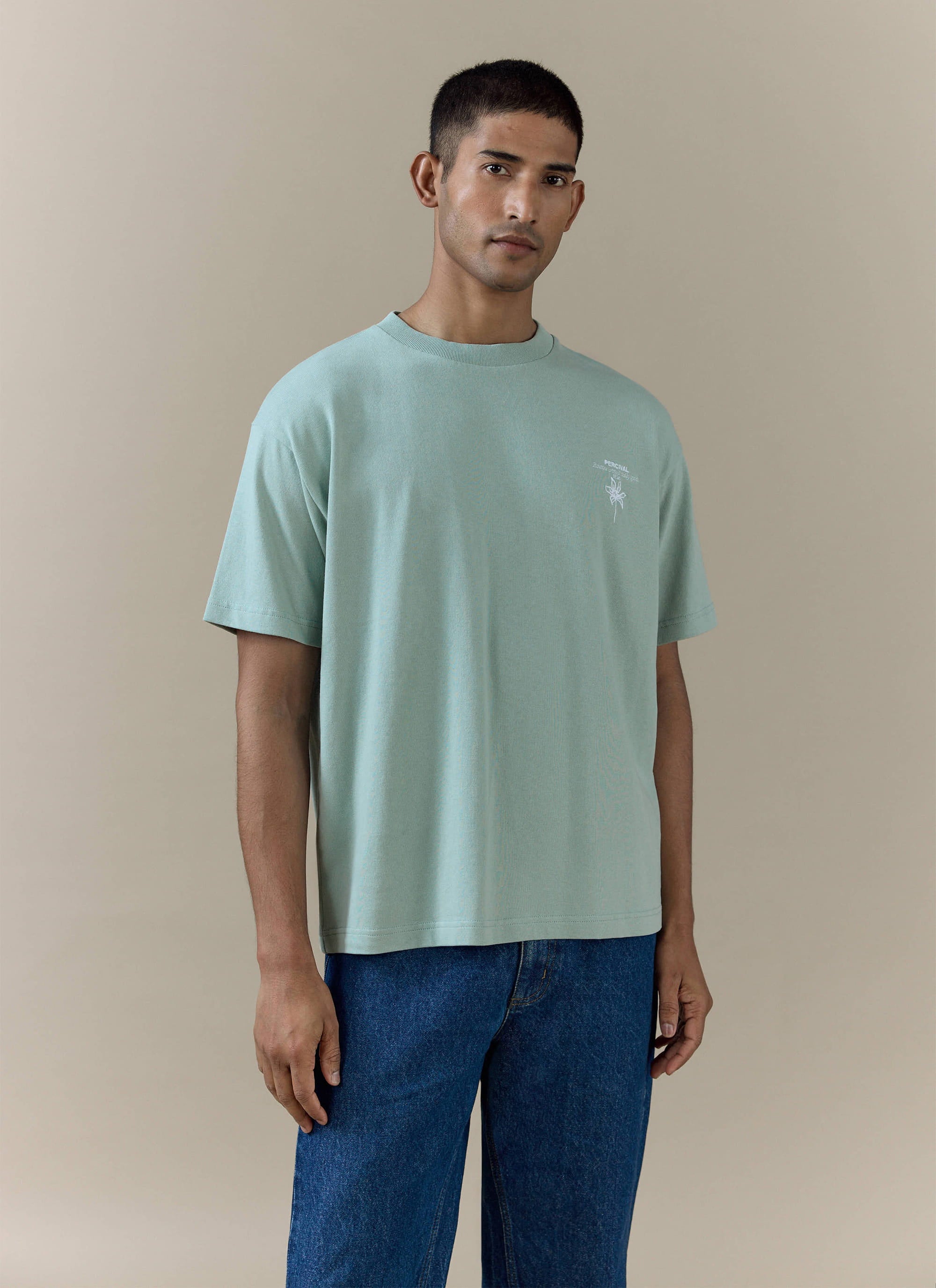 Percival's sage green Melvin Oversized T Shirt in organic cotton, featuring a small chest graphic and relaxed fit.