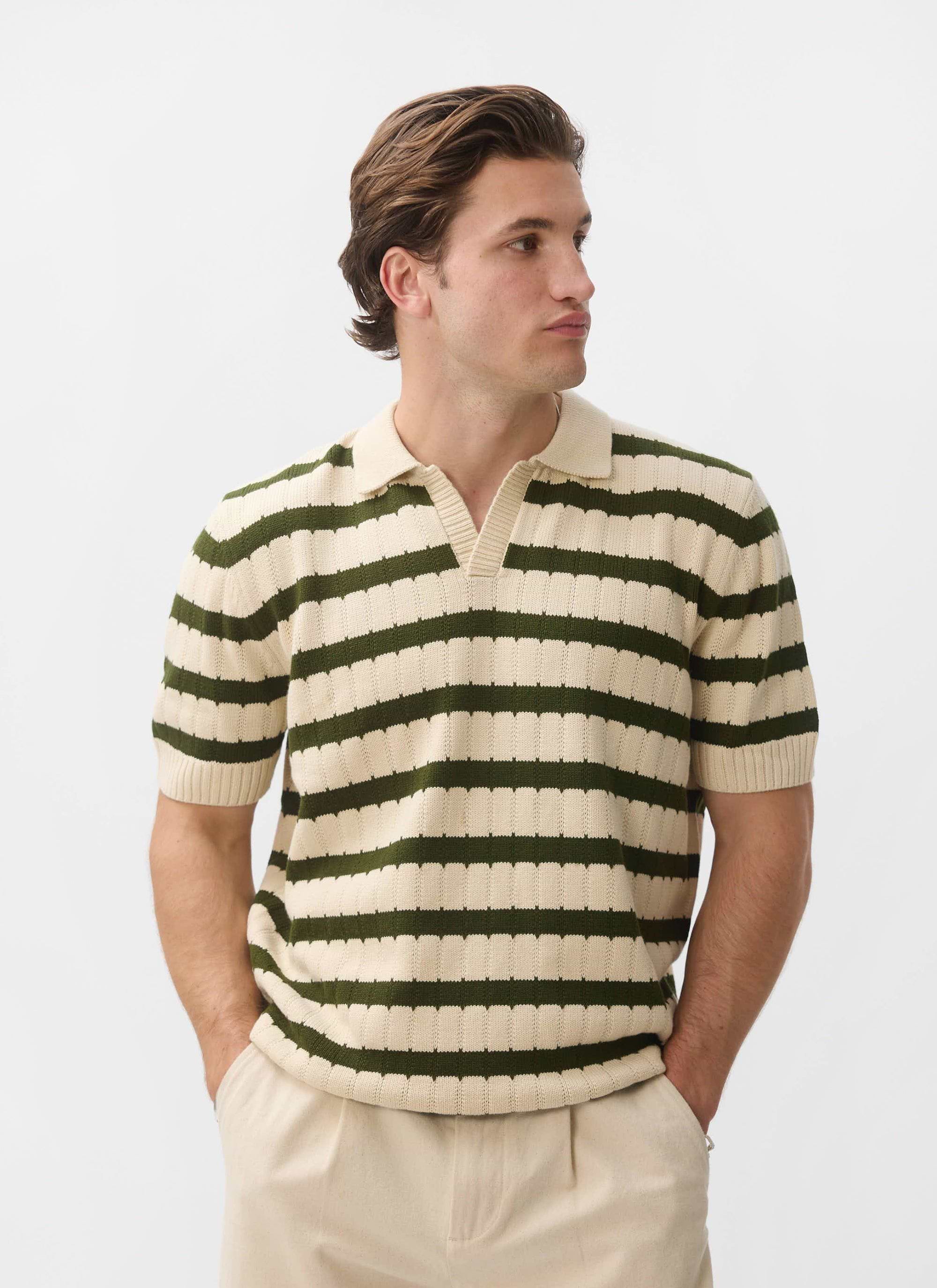A model wears the Percival Stine Knitted Polo, an ecru jacquard knit with green stripes, against a white studio background.