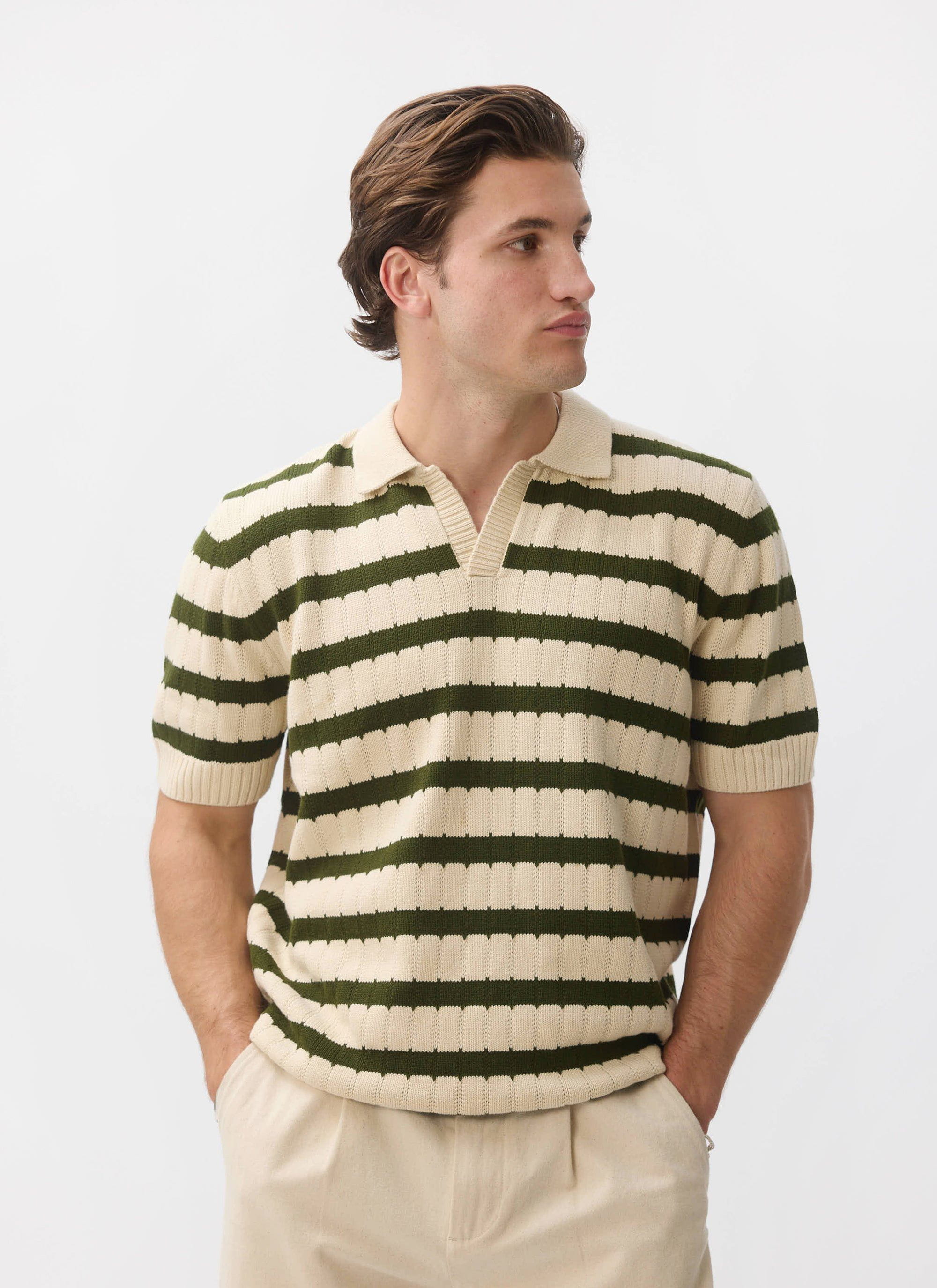 A model wears the Percival Stine Knitted Polo, an ecru jacquard knit with green stripes, against a white studio background.