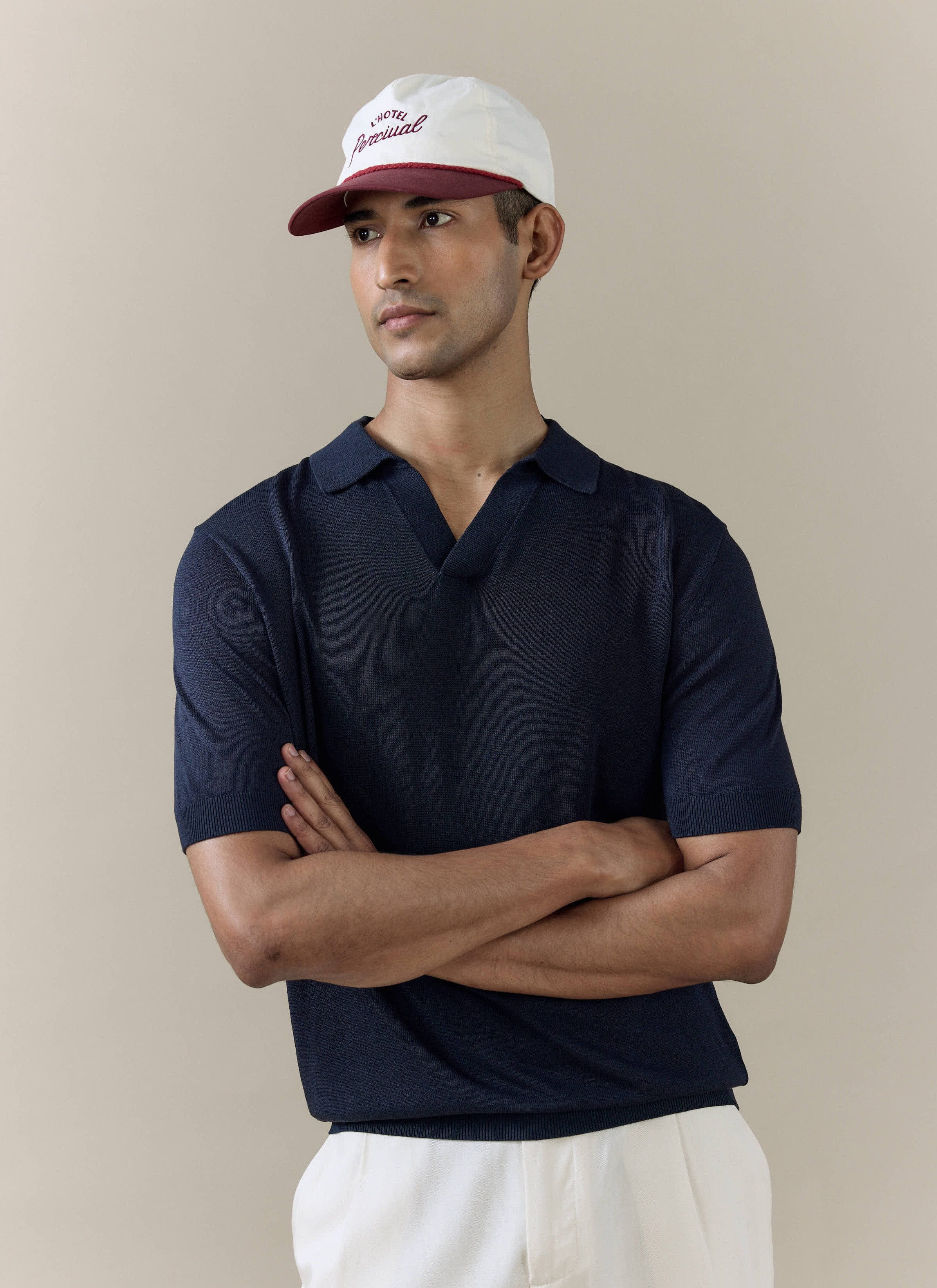 A model wears the navy Laurence Knitted Polo by Percival, featuring an open V placket and breathable linen lyocell blend.