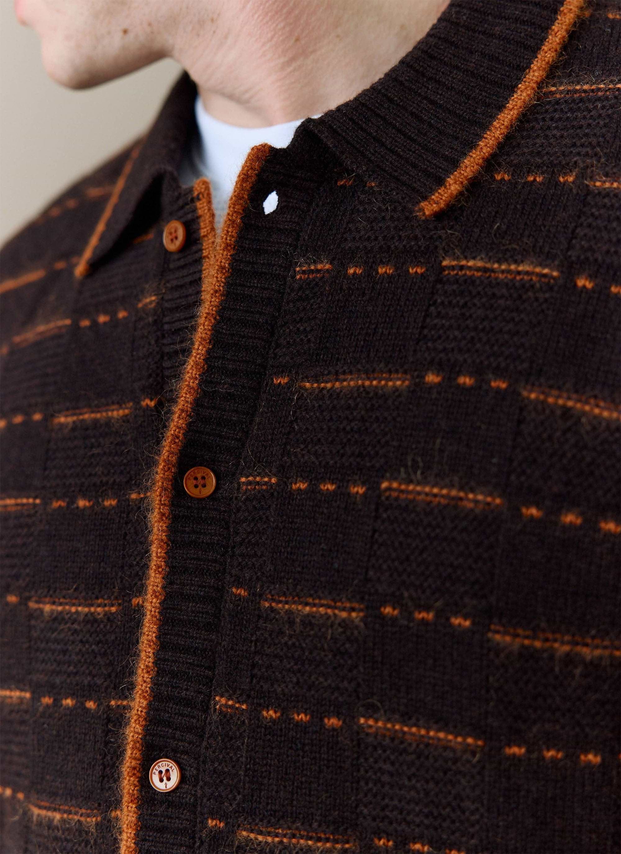 Close-up of a model wearing the brown Addison Knitted Shirt from Percival, showing the orange stitching and branded buttons.