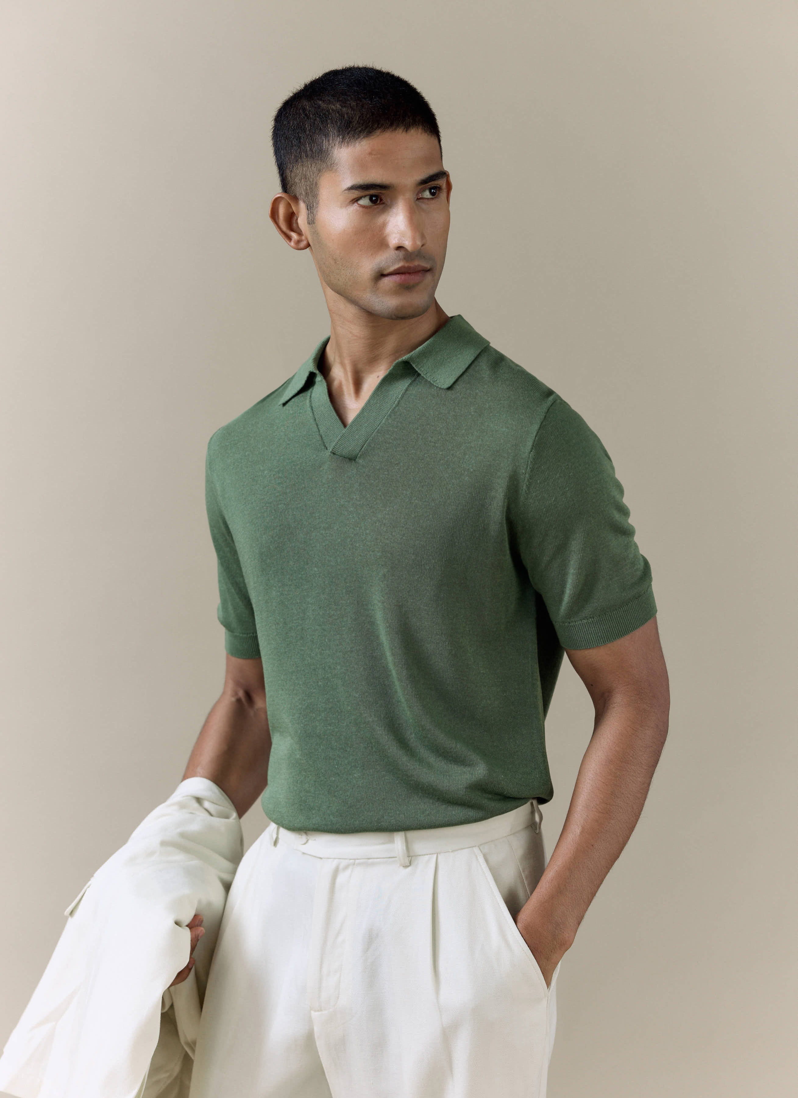 Percival Laurence Knitted Polo in forest green linen lyocell blend, styled with cream trousers on a model.