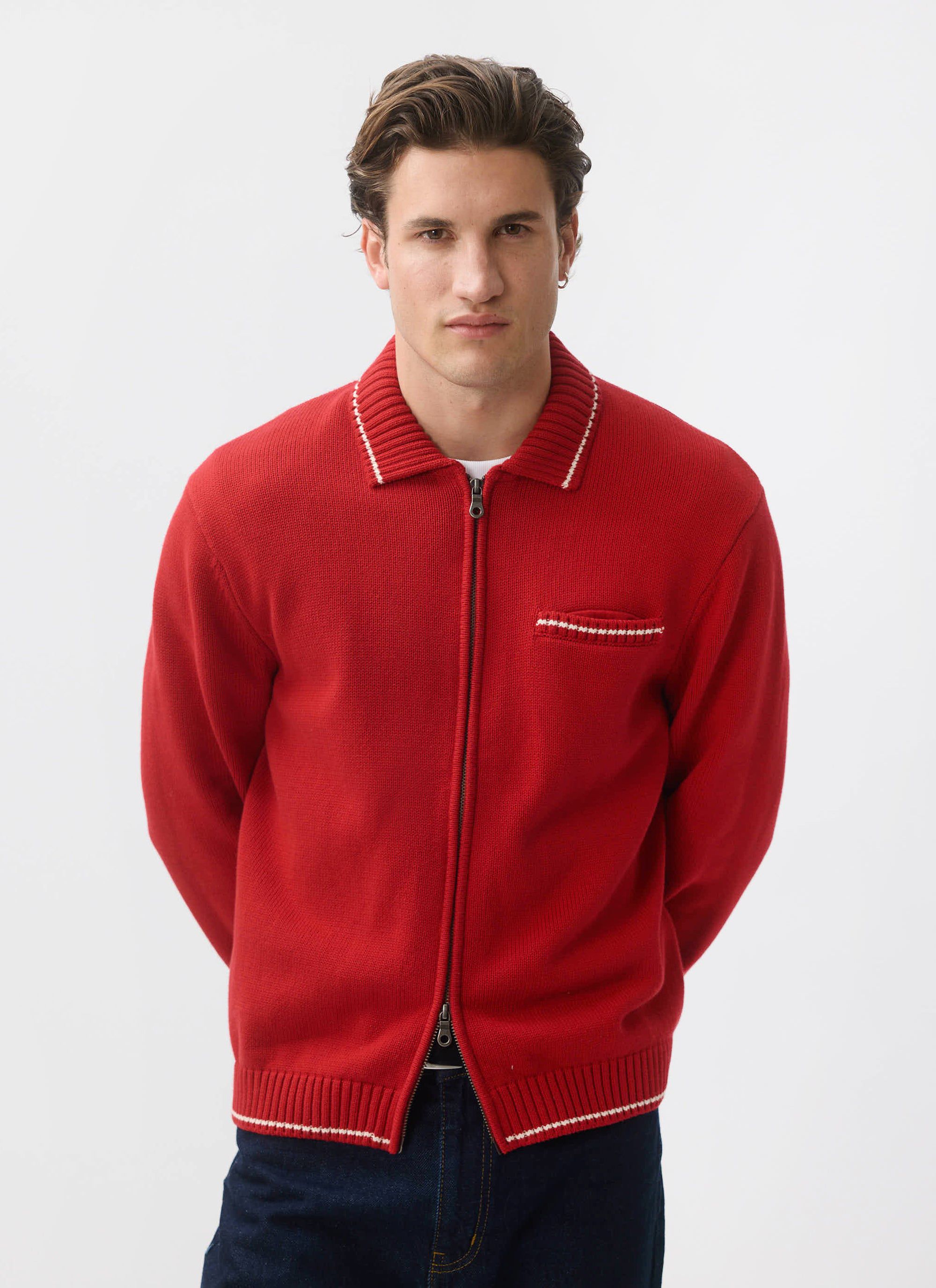 A model wears the Percival Gardner Dense Knitted Zip Cardigan in red, posing against a clean white studio background.