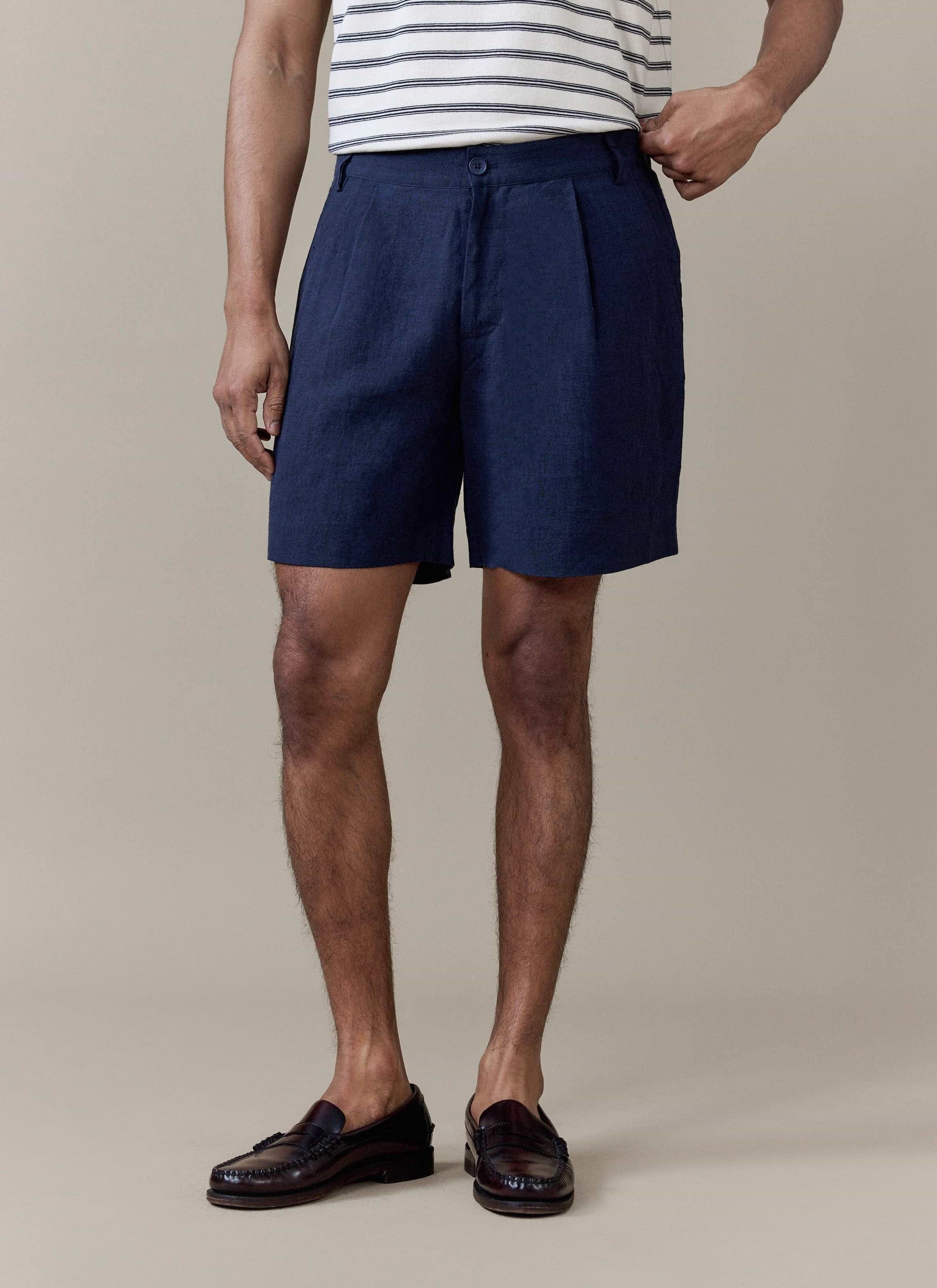 Navy pleated linen shorts by Percival, featuring a tailored fit and styled with dark brown leather loafers.