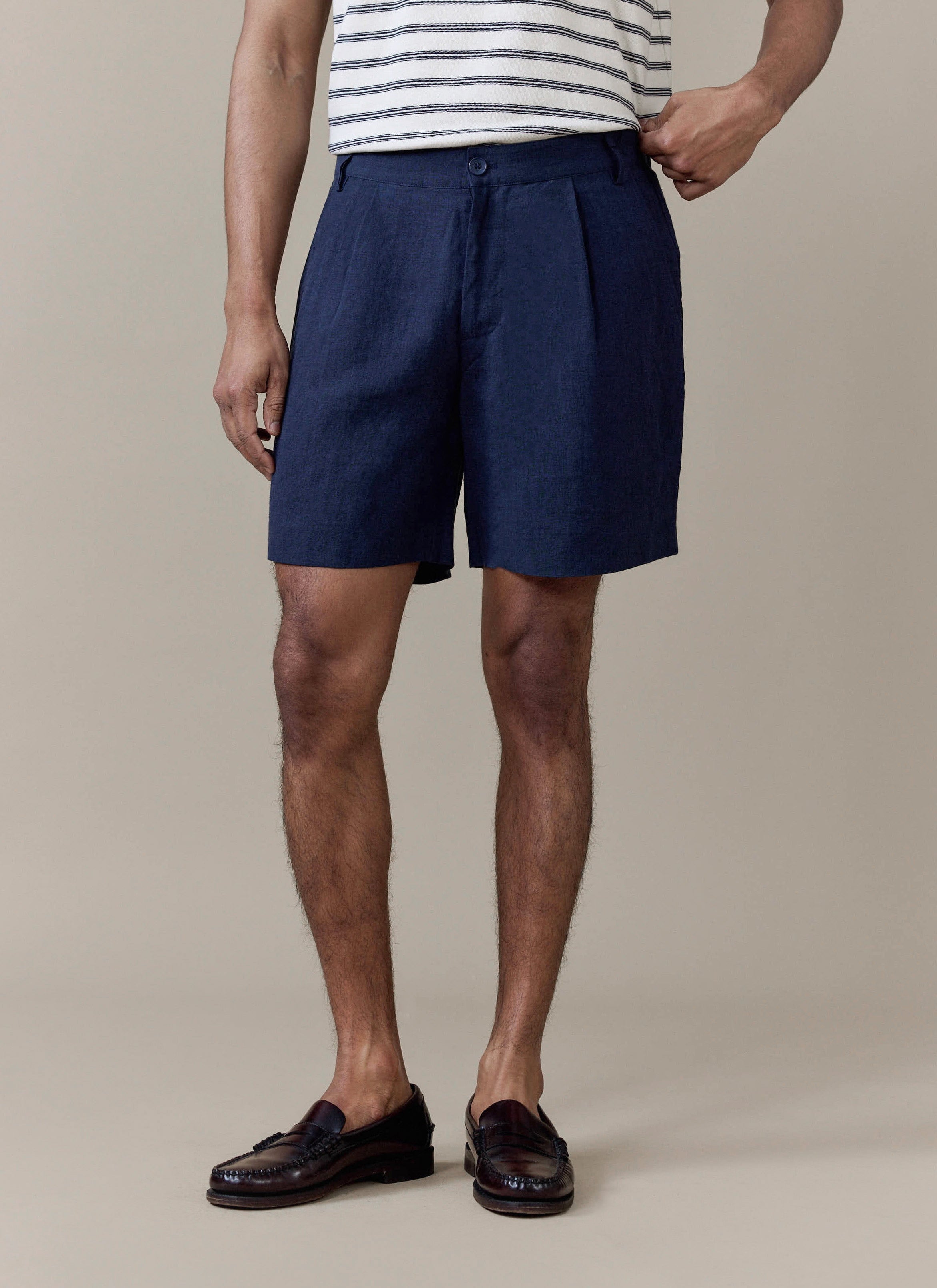Navy pleated linen shorts by Percival, featuring a tailored fit and styled with dark brown leather loafers.
