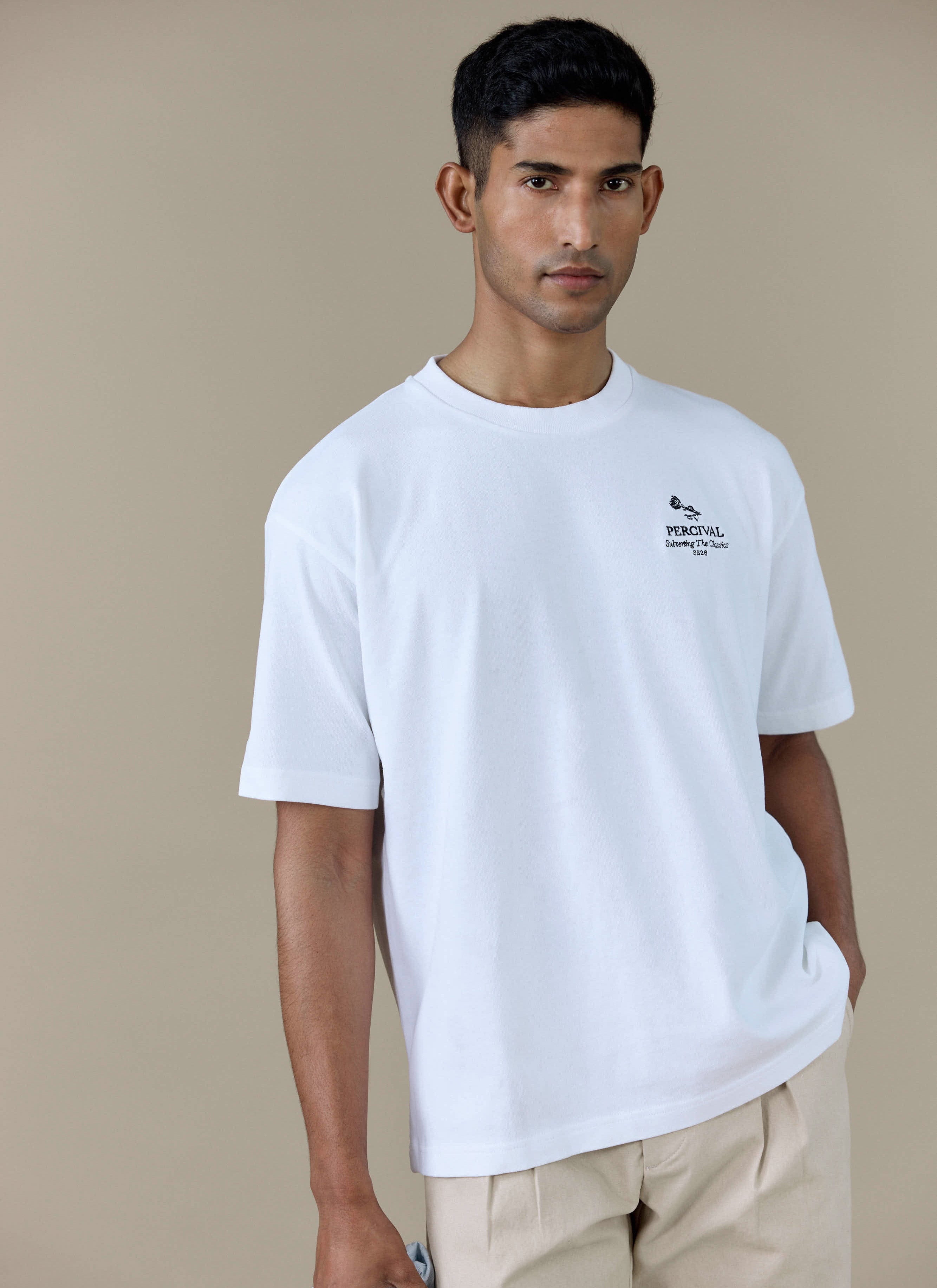 A model wearing the white Perci Waters Oversized T Shirt by Percival, featuring subtle chest embroidery.