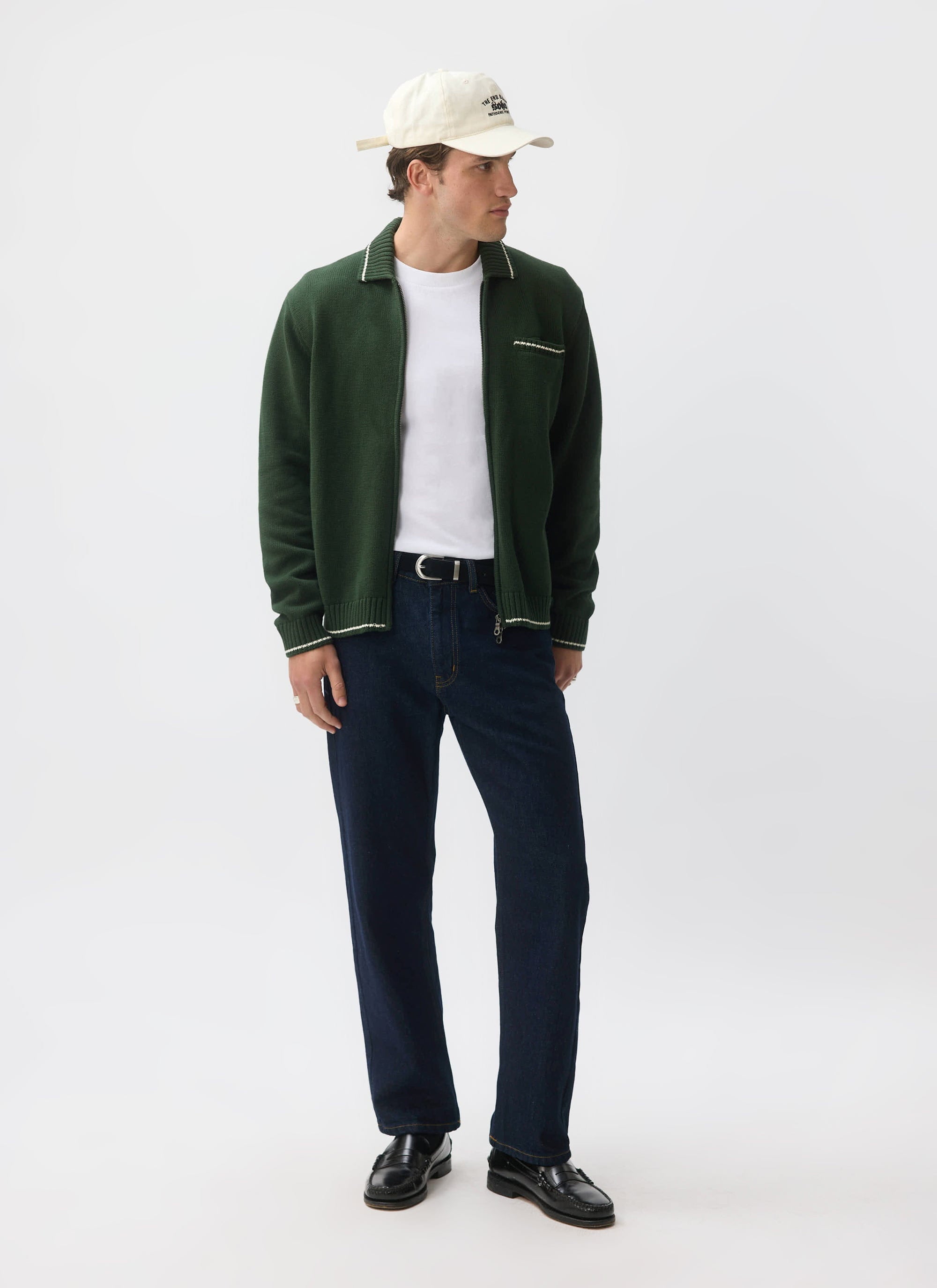 A model wears the Percival Gardner Knitted Zip Cardigan in forest green, styled over a white t-shirt with dark jeans.
