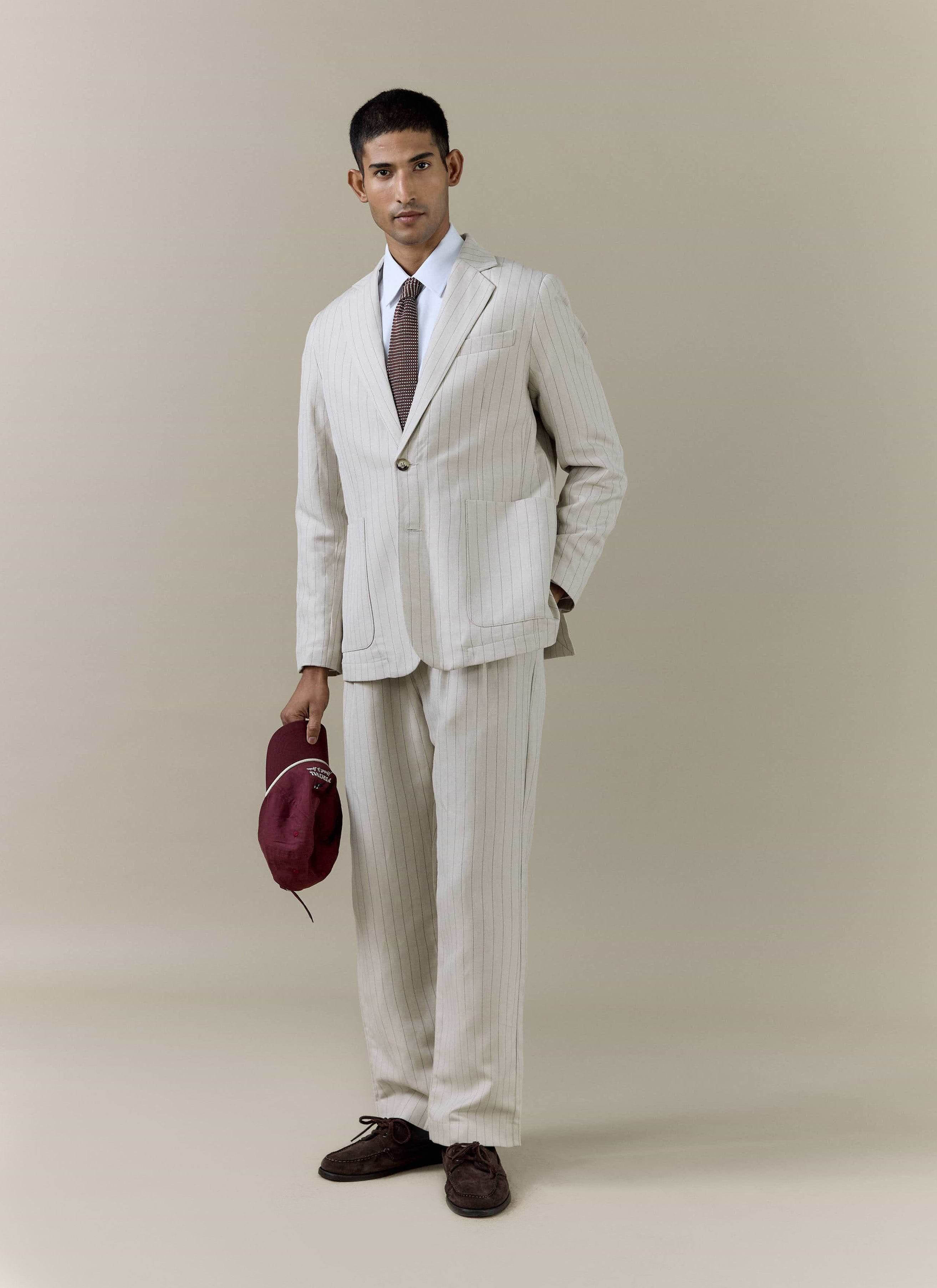 Cream striped linen blazer and matching pleated trousers by Percival, styled as a full-length summer suit.