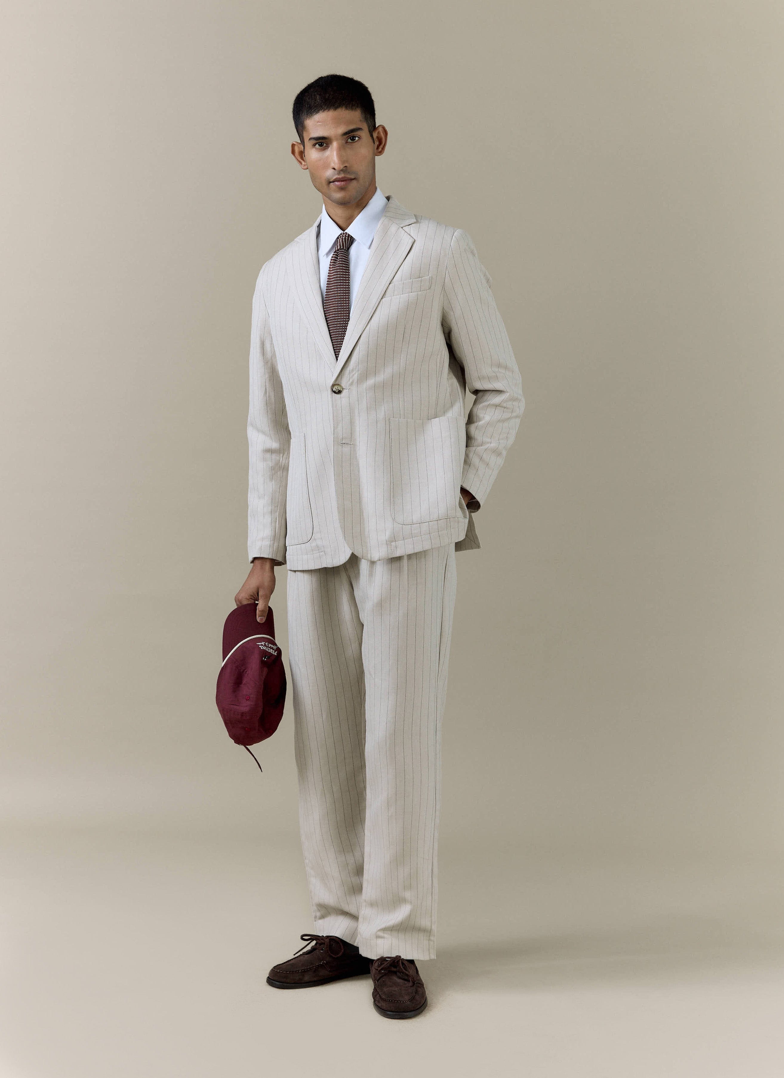 Cream striped linen blazer and matching pleated trousers by Percival, styled as a full-length summer suit.