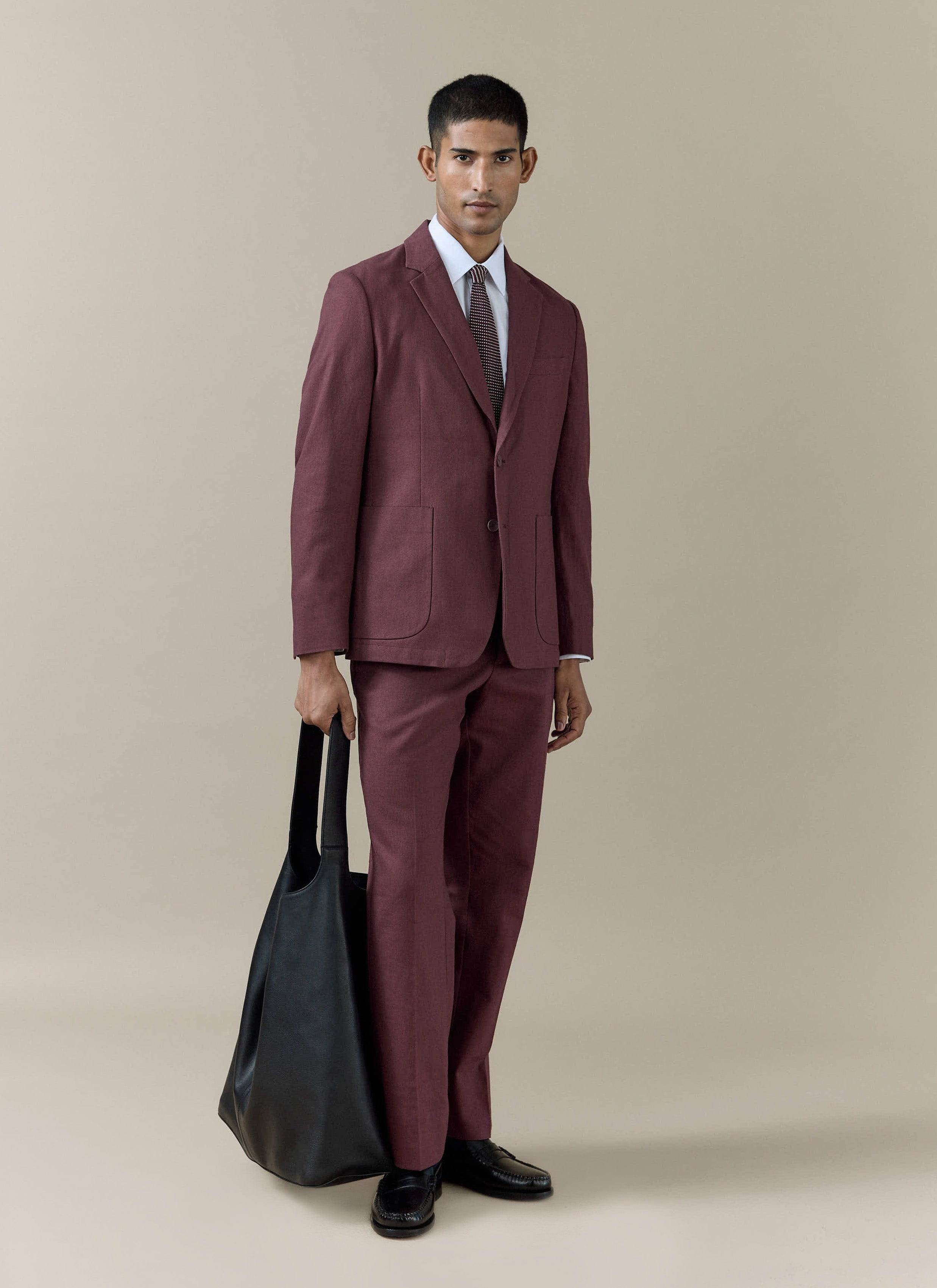 Model wears the merlot Percival Tailored Linen Blazer and matching trousers, styled with a black tote bag.