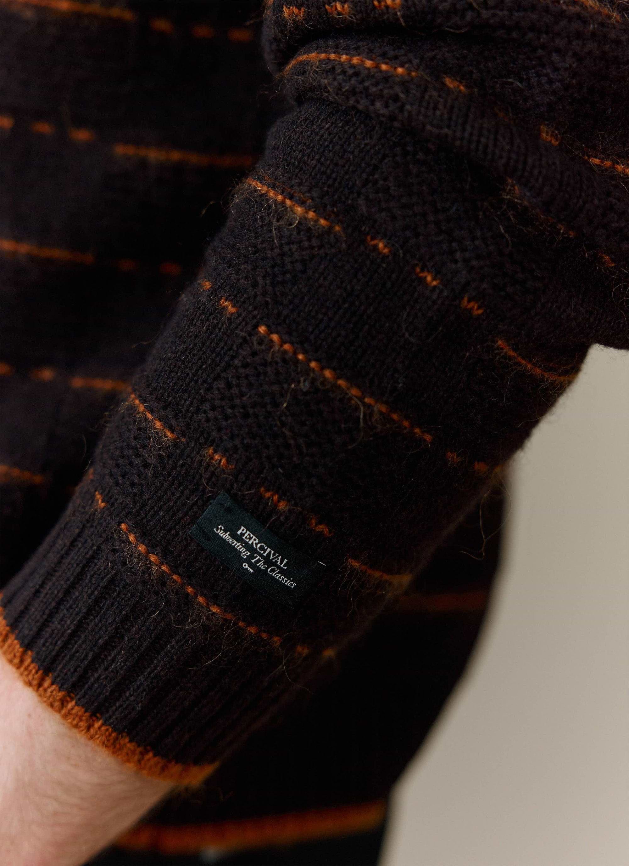 A close-up of the cuff on the brown wool Addison Knitted Shirt, showing the orange stitch detail and Percival label.