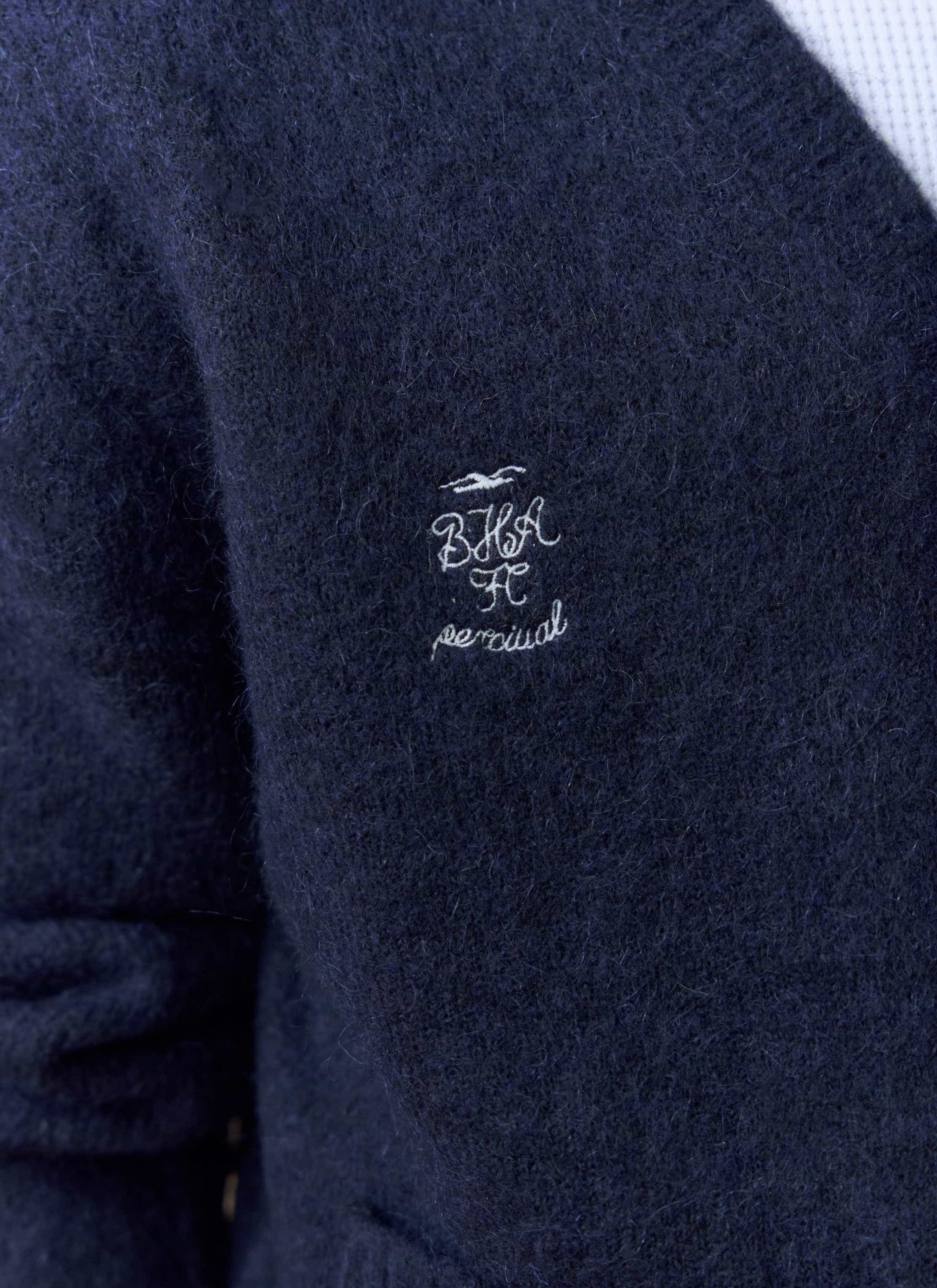 A close-up of the embroidered Percival x Brighton & Hove Albion F.C. logo on the chest of the navy White Glove Cardigan.