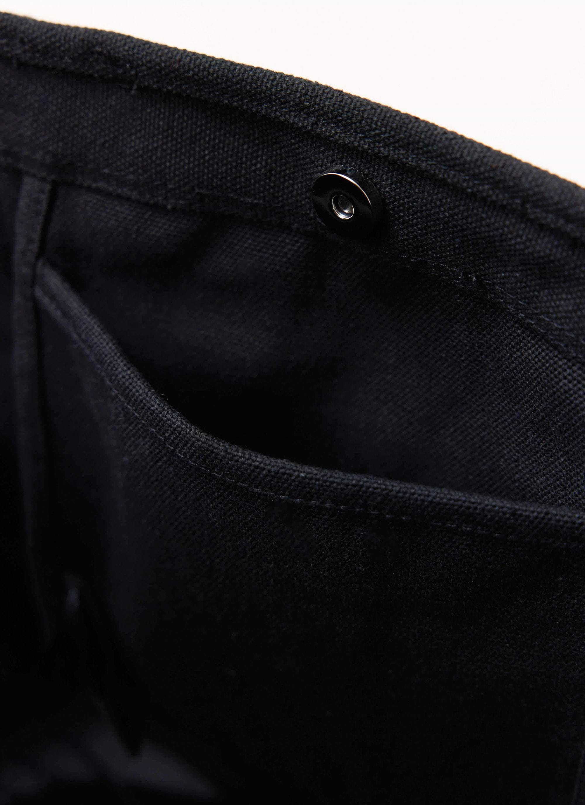 A close-up of the internal pocket and magnetic snap closure on the black canvas tote bag by Percival.