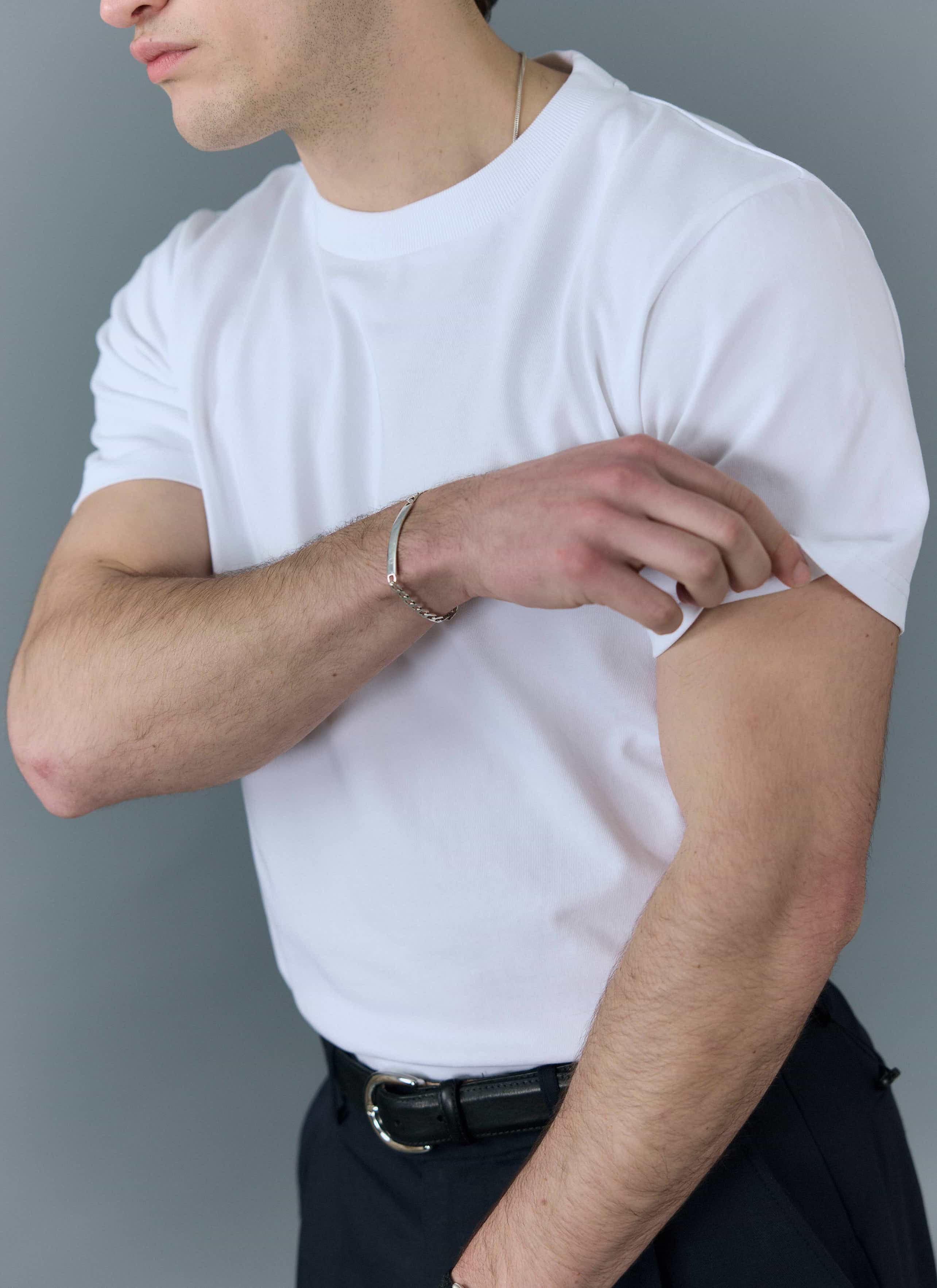Close up of a man wearing the Percival plain white t-shirt and rolling up the short sleeve.