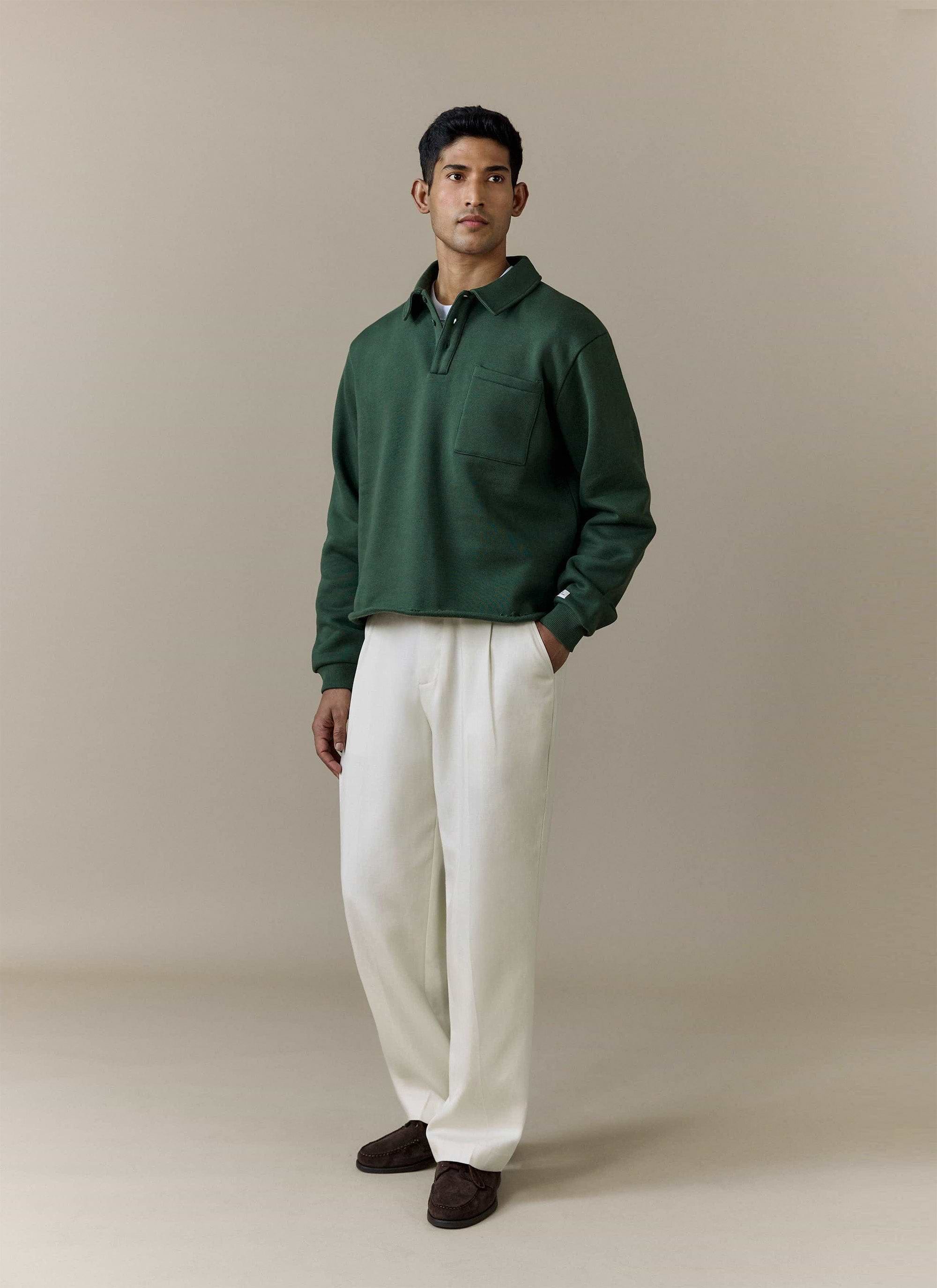 Full-length studio shot of a model wearing the Percival Dudley Boxy Sweatshirt in Forest with cream trousers.