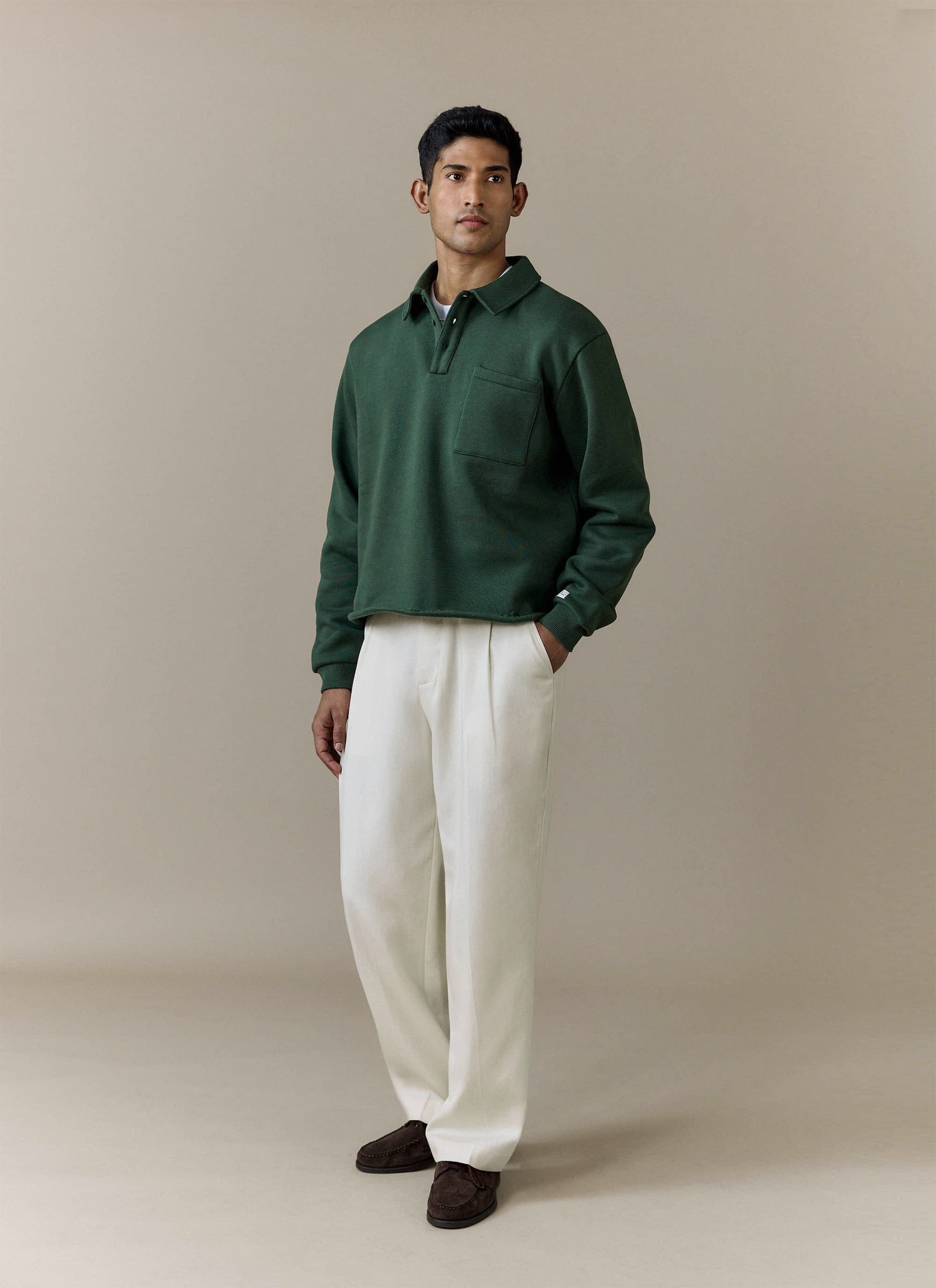 Full-length studio shot of a model wearing the Percival Dudley Boxy Sweatshirt in Forest with cream trousers.