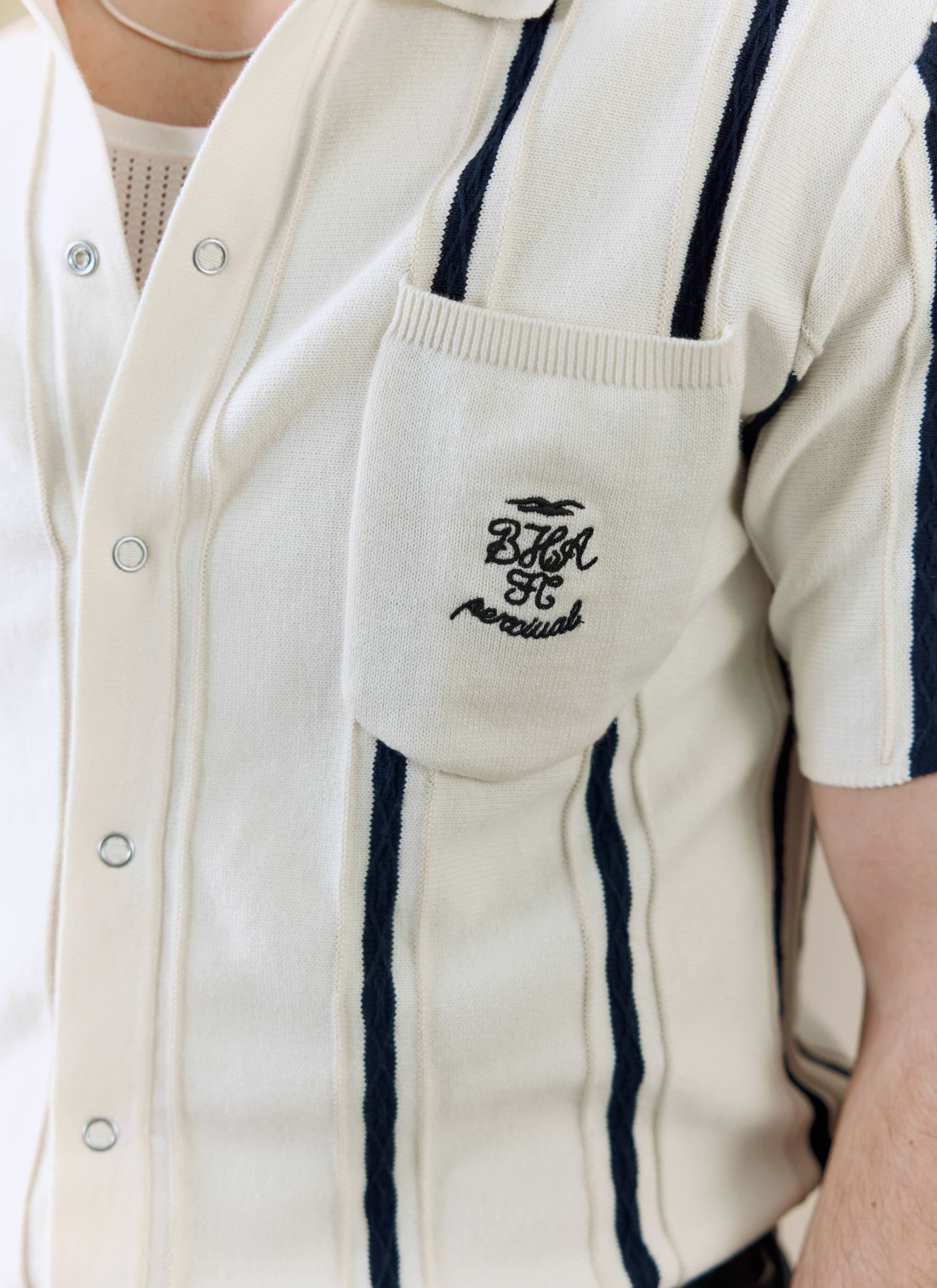 Close-up of the embroidered chest pocket on the Percival x Brighton & Hove Albion F.C. Cable Stripe Knitted Shirt in white.