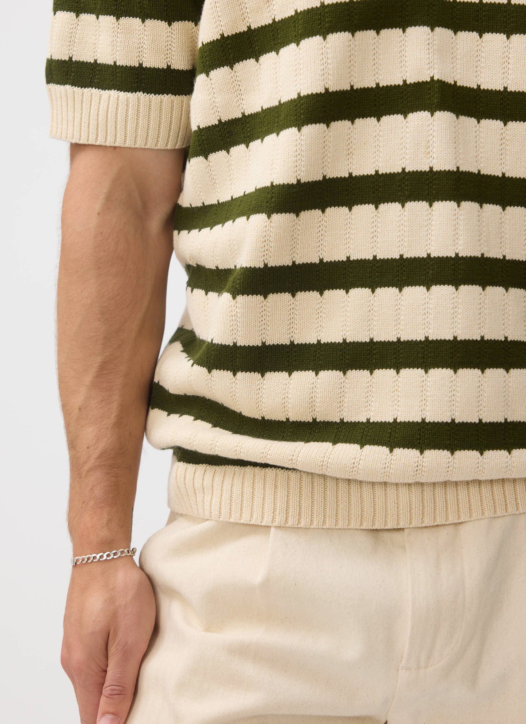 Side-profile close-up of a model in the Percival Stine Knitted Polo, highlighting the ecru and green jacquard stripes.