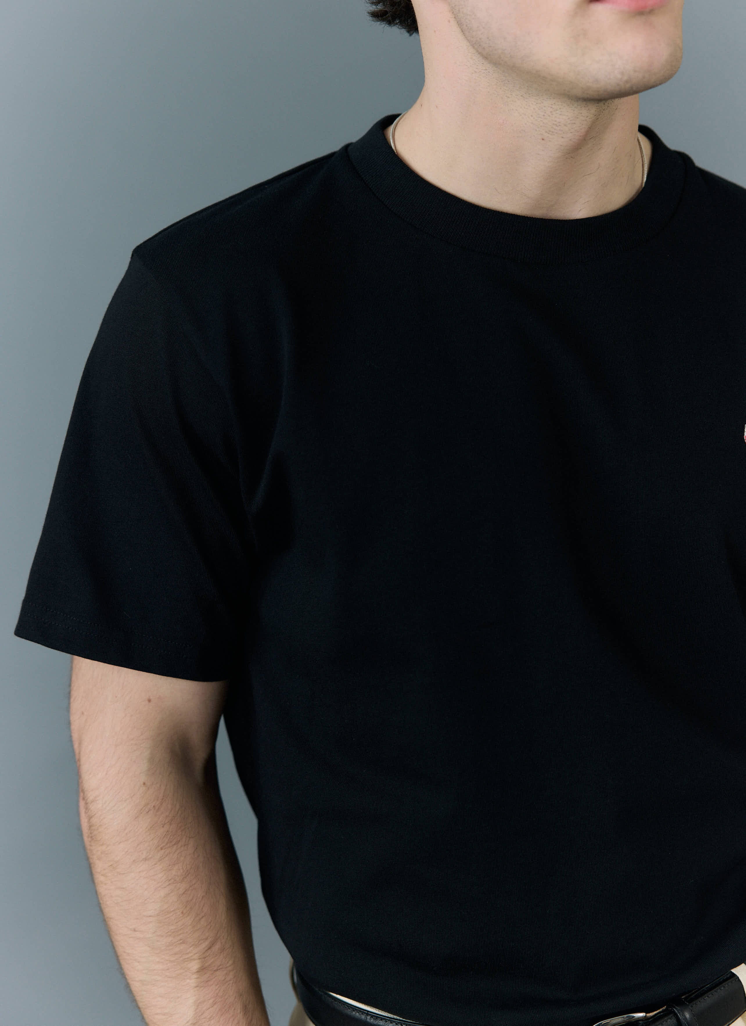 A close-up of a model wearing the Percival regular fit t-shirt in black organic cotton.