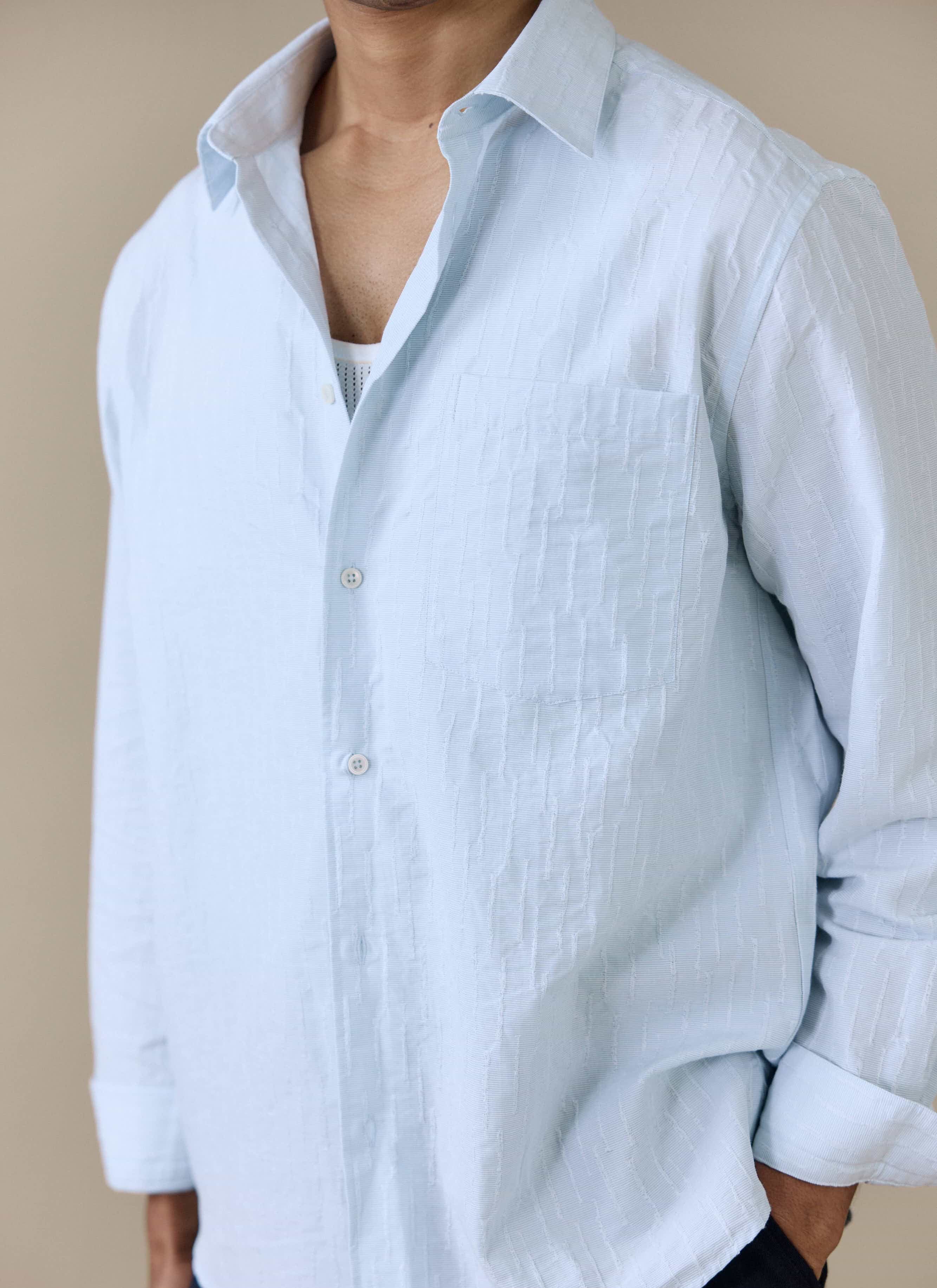 Close-up of the light blue Paros Pearce Shirt by Percival, showing the textured seersucker weave and chest pocket detail.