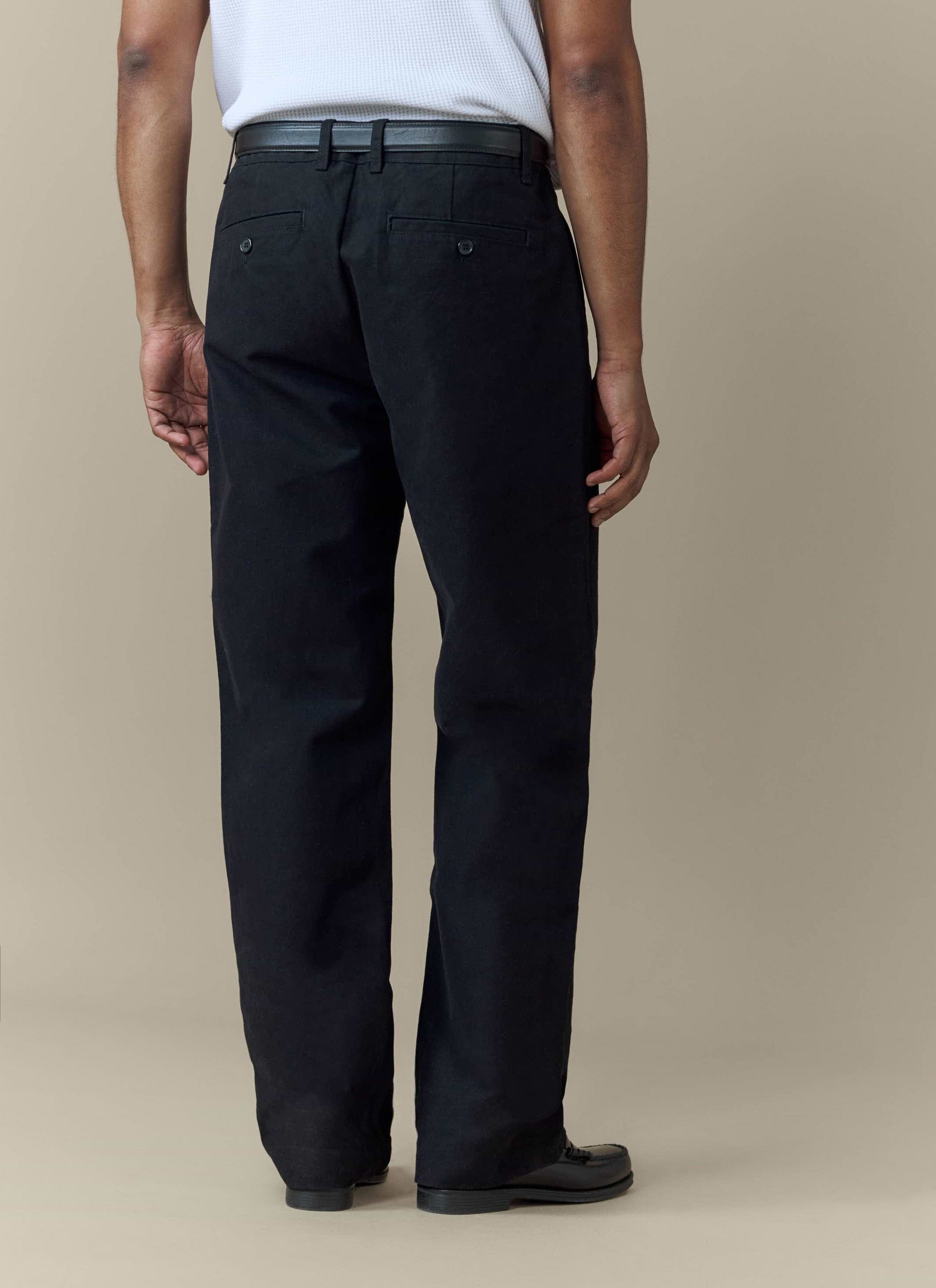 The back view of a model wearing the black Seb Inverted Pleat Trousers by Percival.