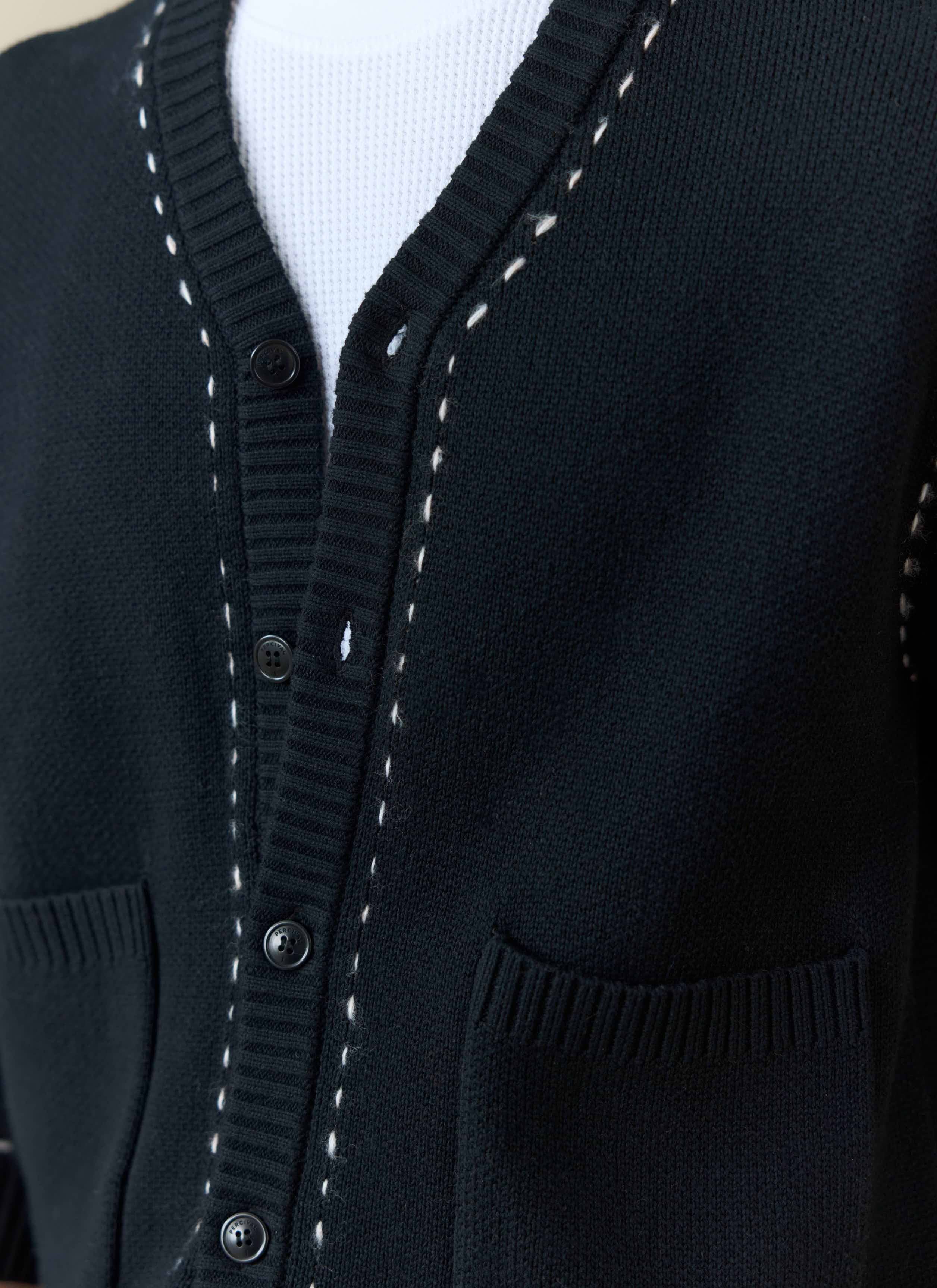 Close-up of the black Percival Module Boxy Cardigan showing the button front, pockets, and white stitch detailing.