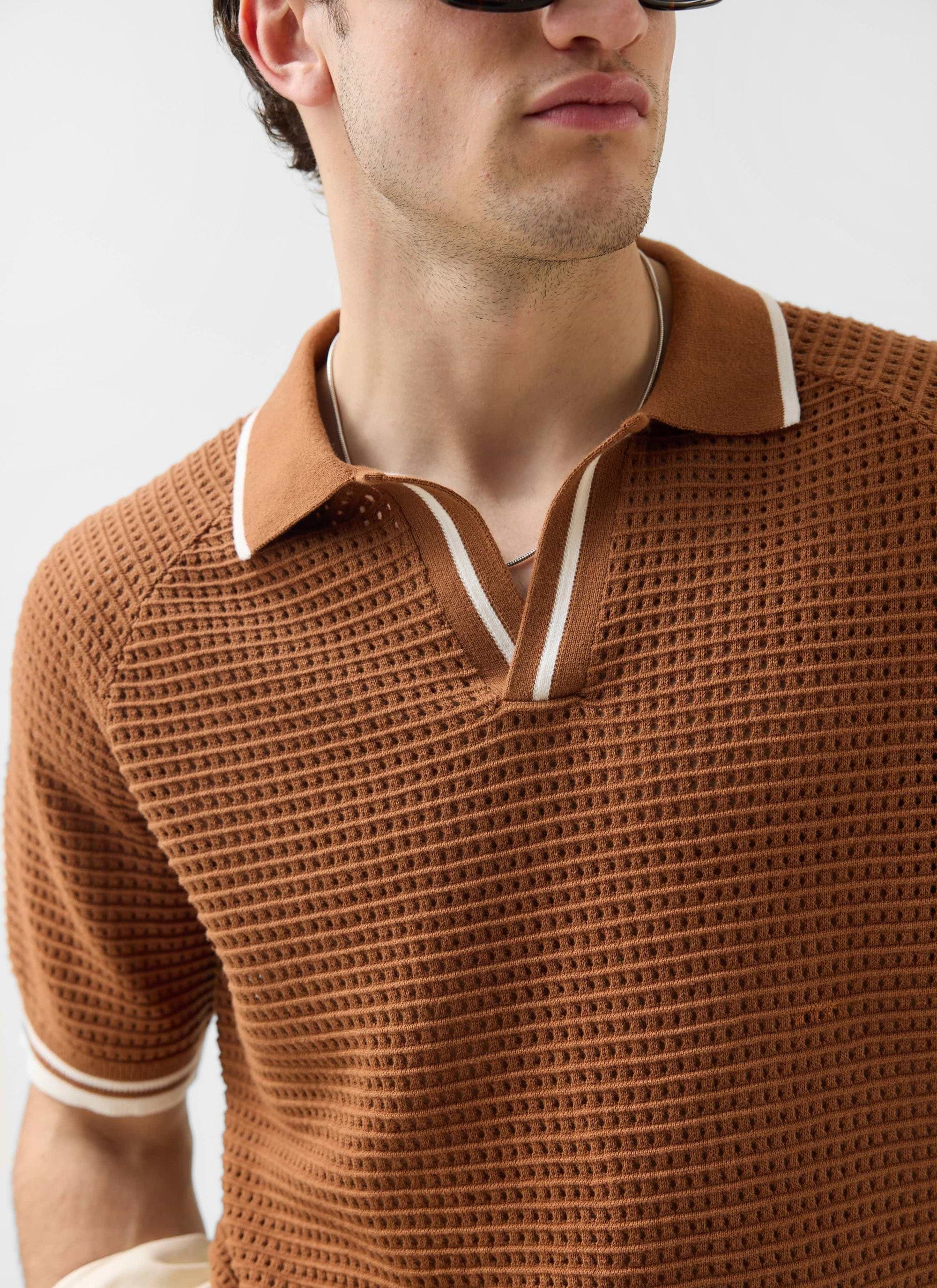 A close-up of a model wearing the Percival Tennis Boxy Knitted Polo in brown, showing the perforated knit and striped collar.
