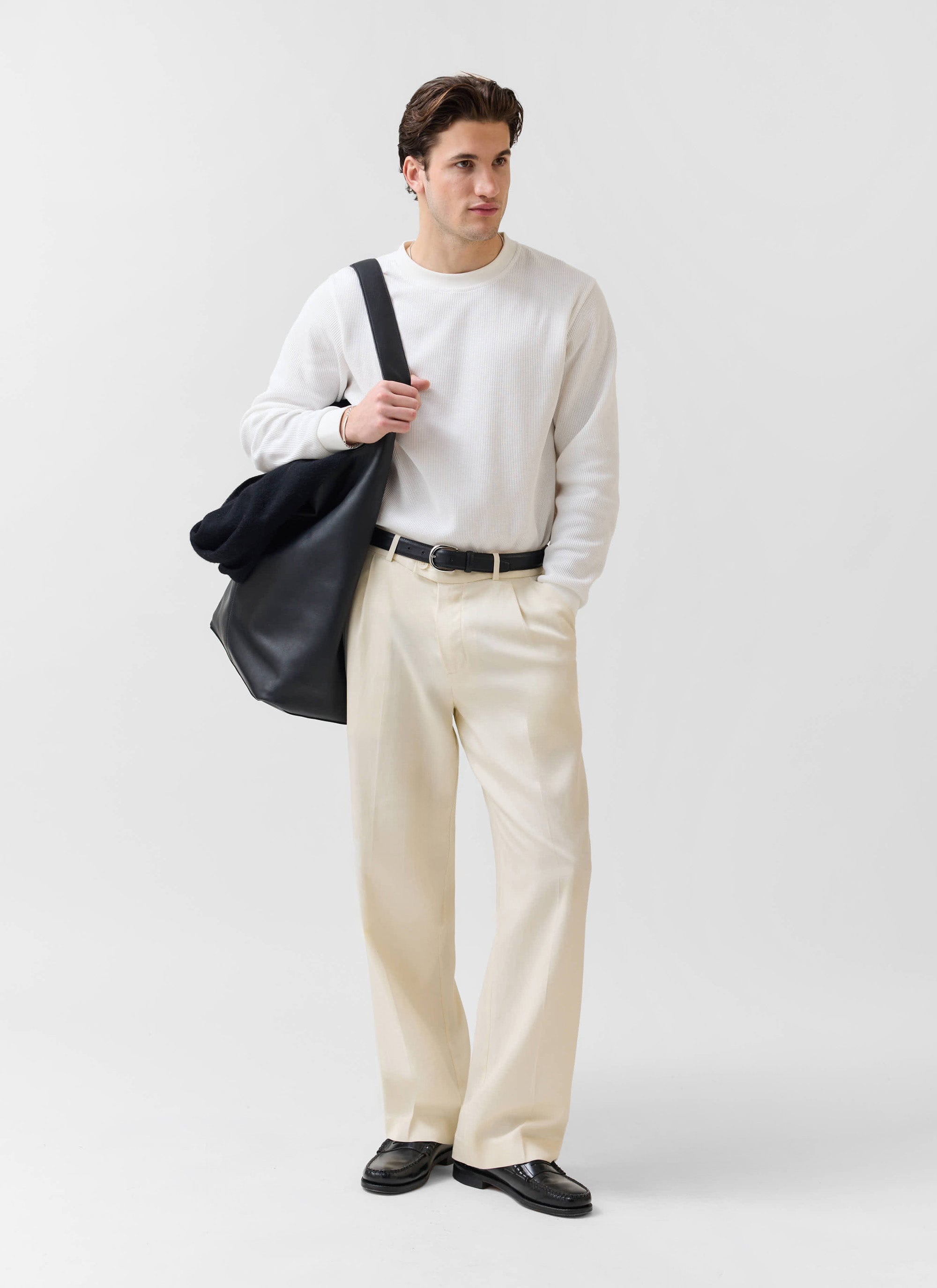 A model wears the white Waffle Long Sleeve T Shirt from Percival, styled with cream trousers and a black tote bag.
