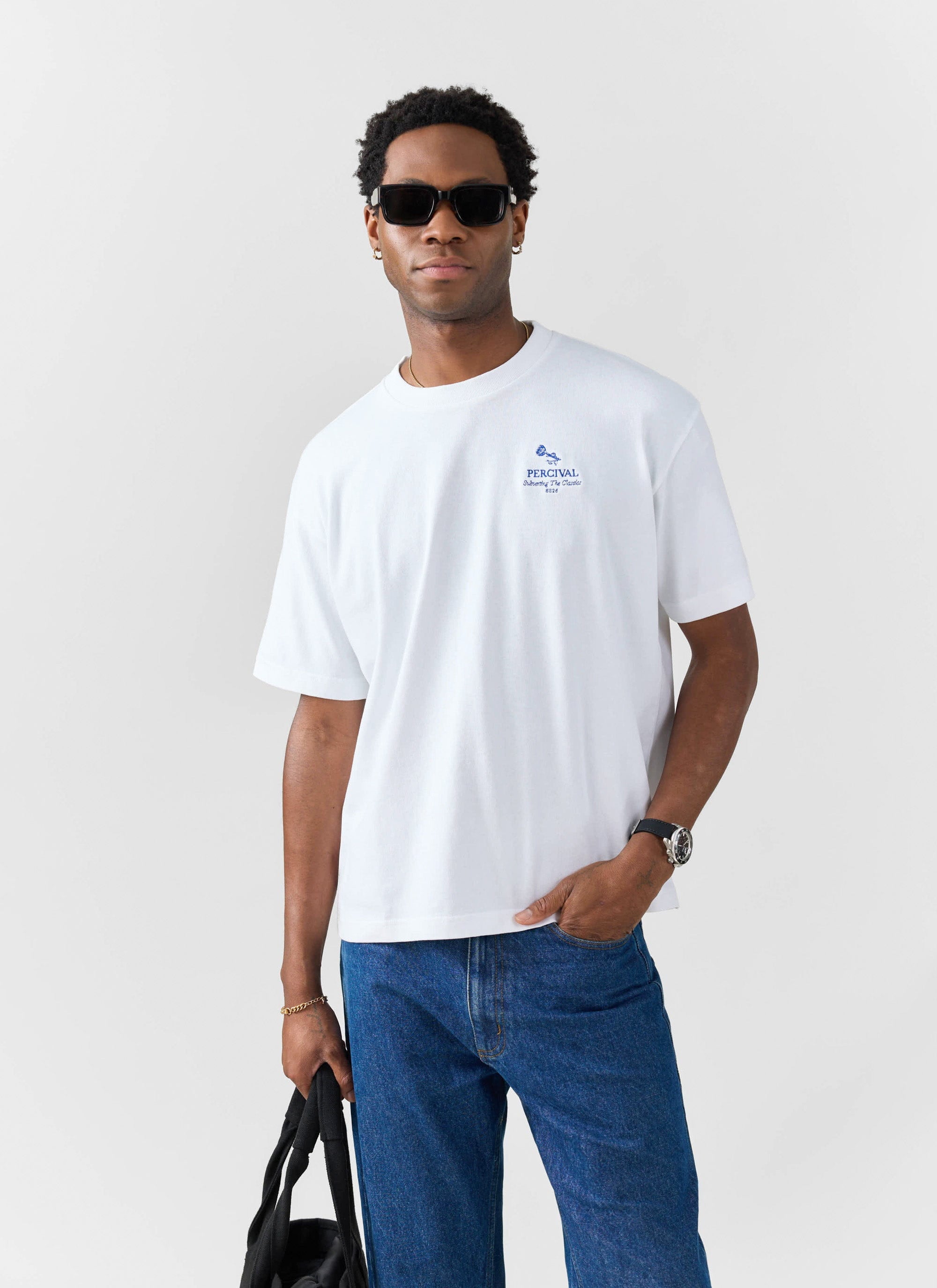A model wears the Percival Smith Floral Oversized T Shirt in white, paired with blue jeans and sunglasses.
