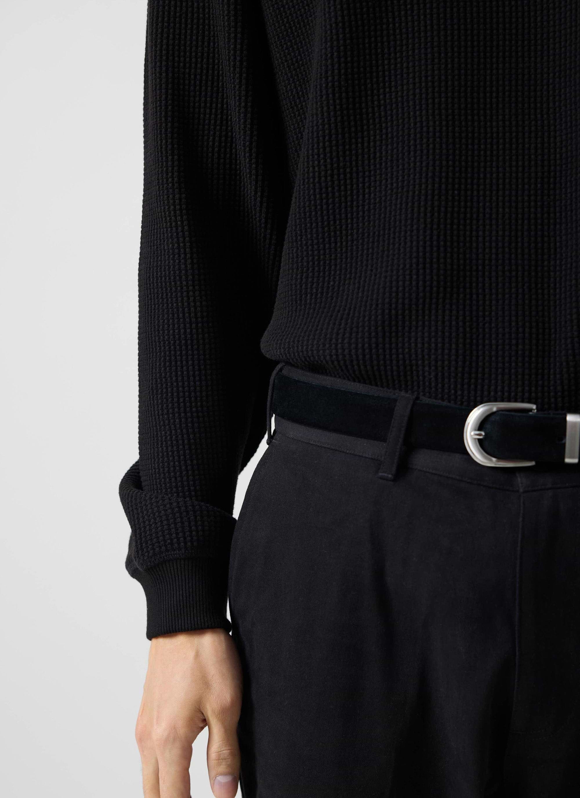 A close up shot of a model wearing the black Waffle Long Sleeve T-shirt from Percival, showing the textured fabric.