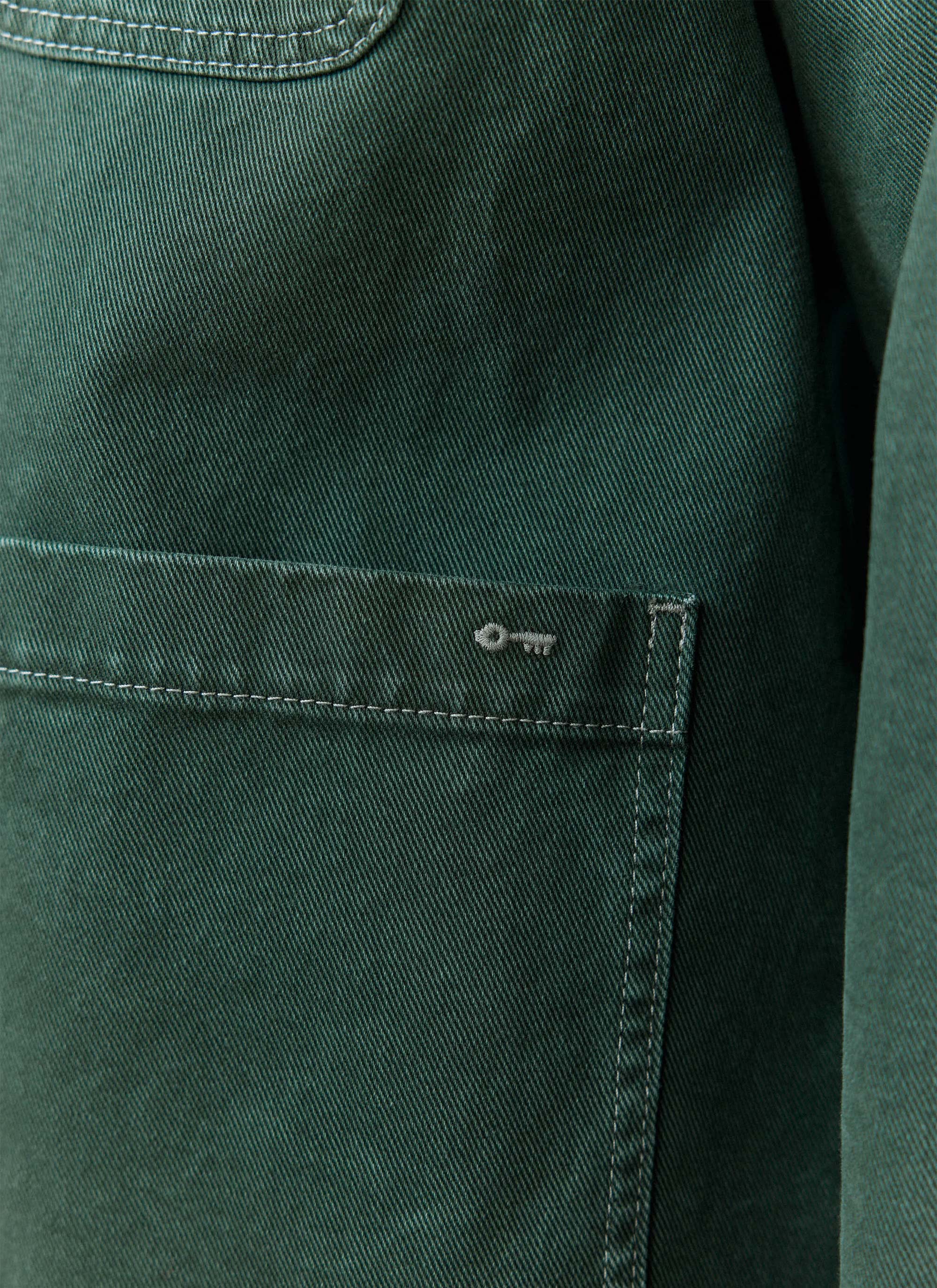 Forest green cotton canvas detail of the Percival Oliver Chore Jacket, showing the signature key embroidery on the pocket.